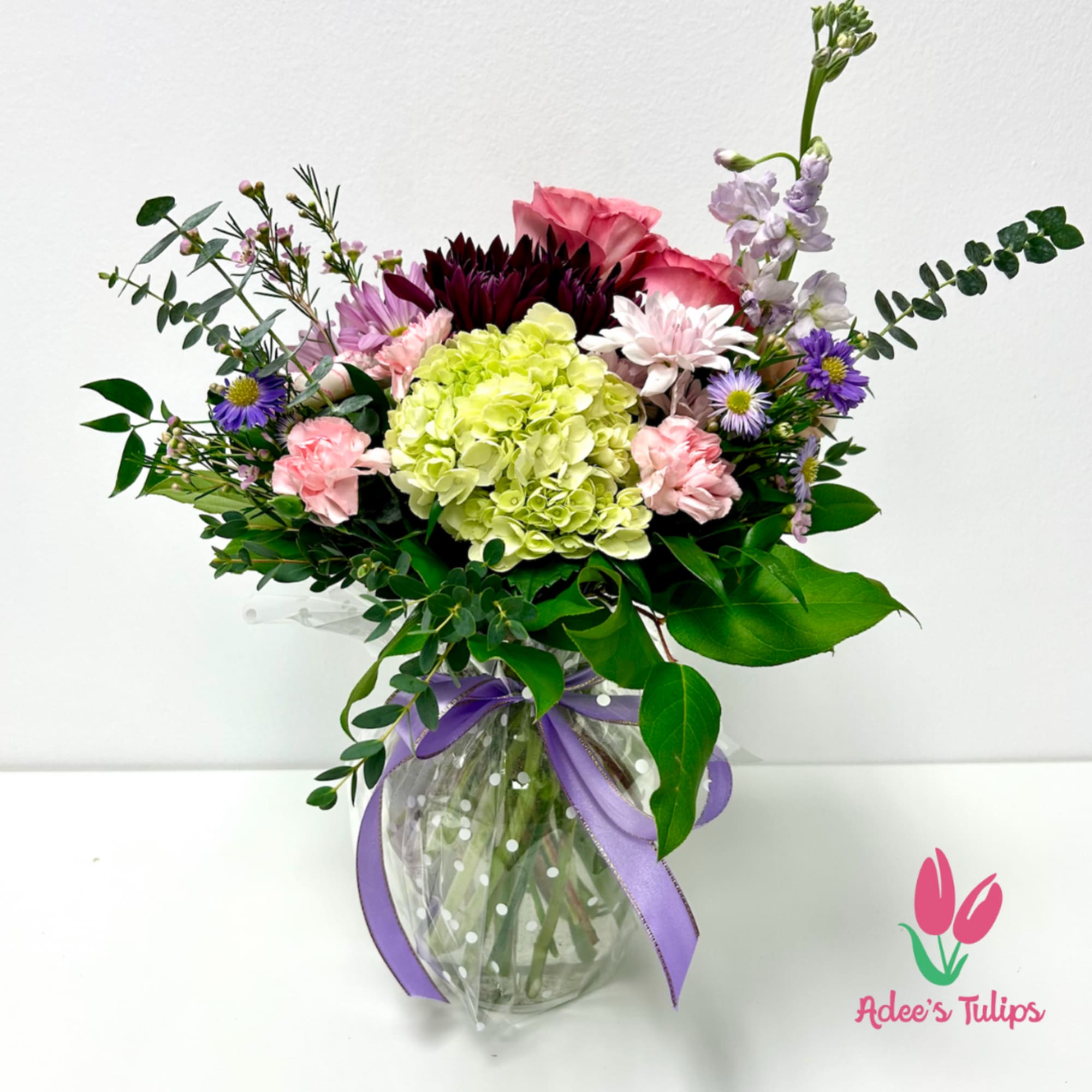 Mixed bouquet in a glass vase with purple ribbon