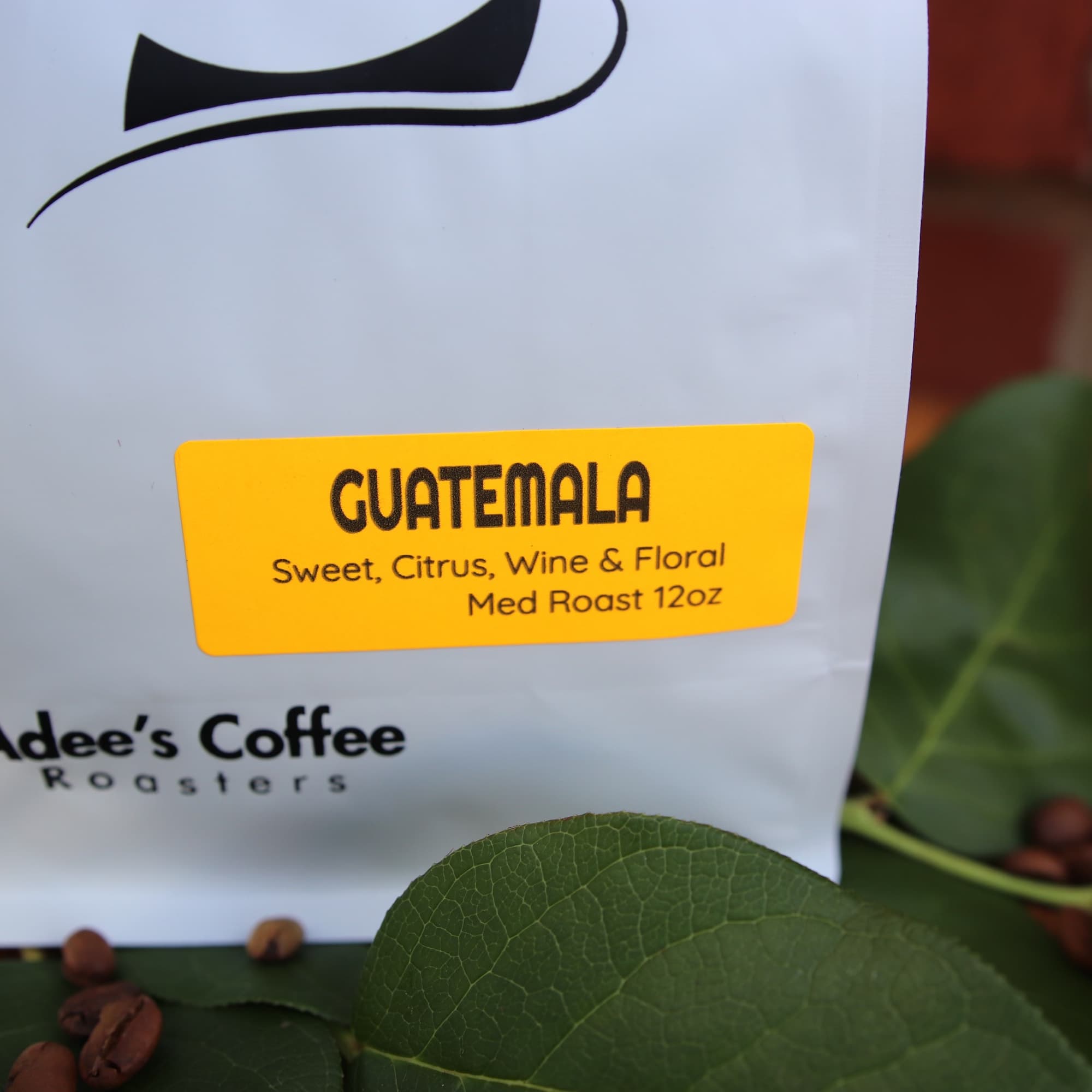 Bag of Guatemala coffee beans with green leaves and scattered beans