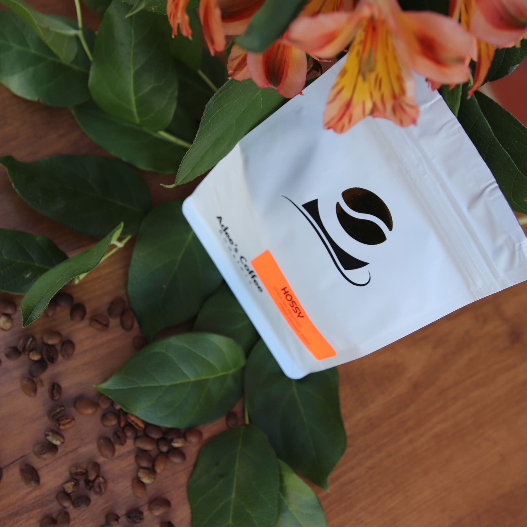 Orange alstroemeria flowers with a white coffee bag and scattered beans