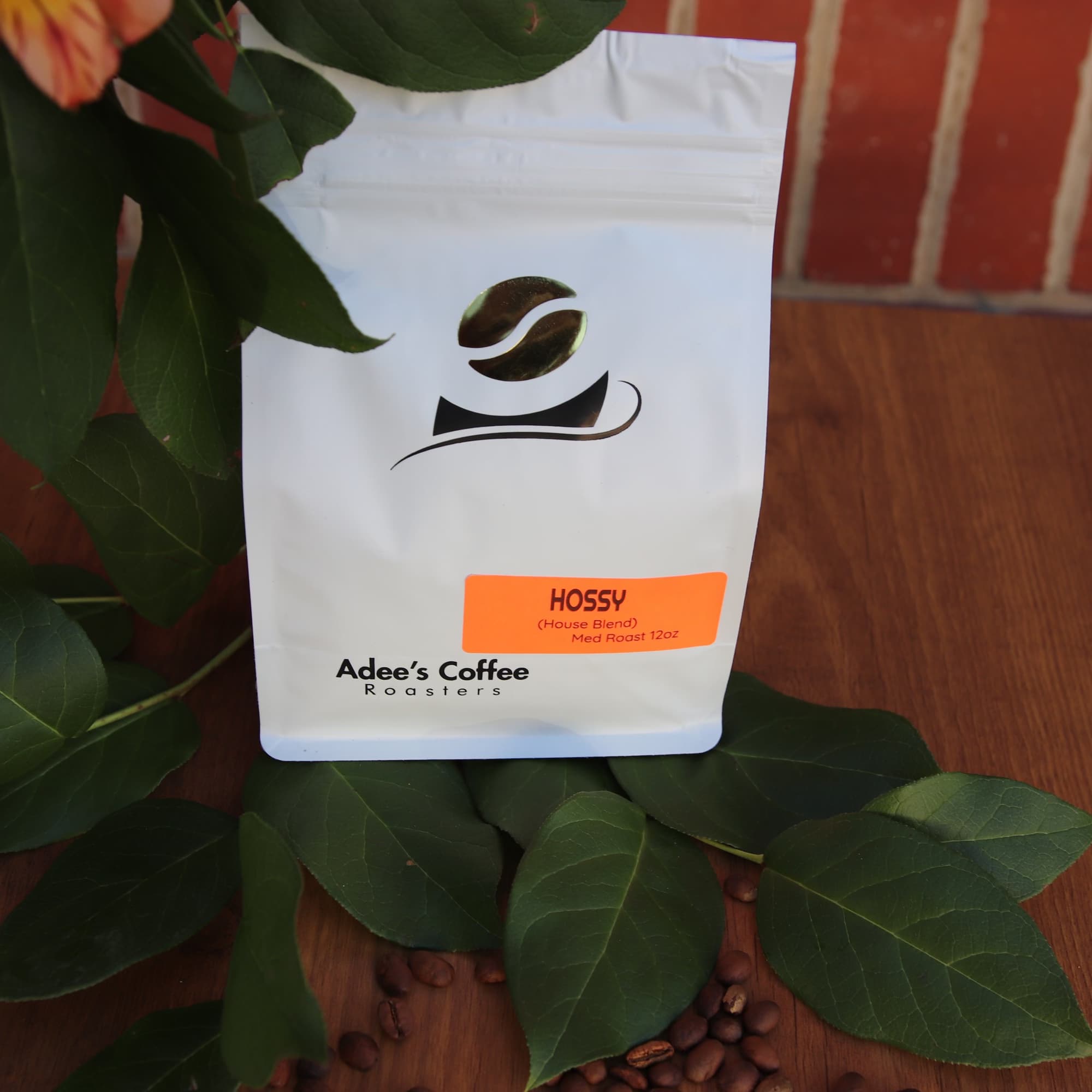 Coffee bag with leaves and scattered coffee beans on a wooden surface