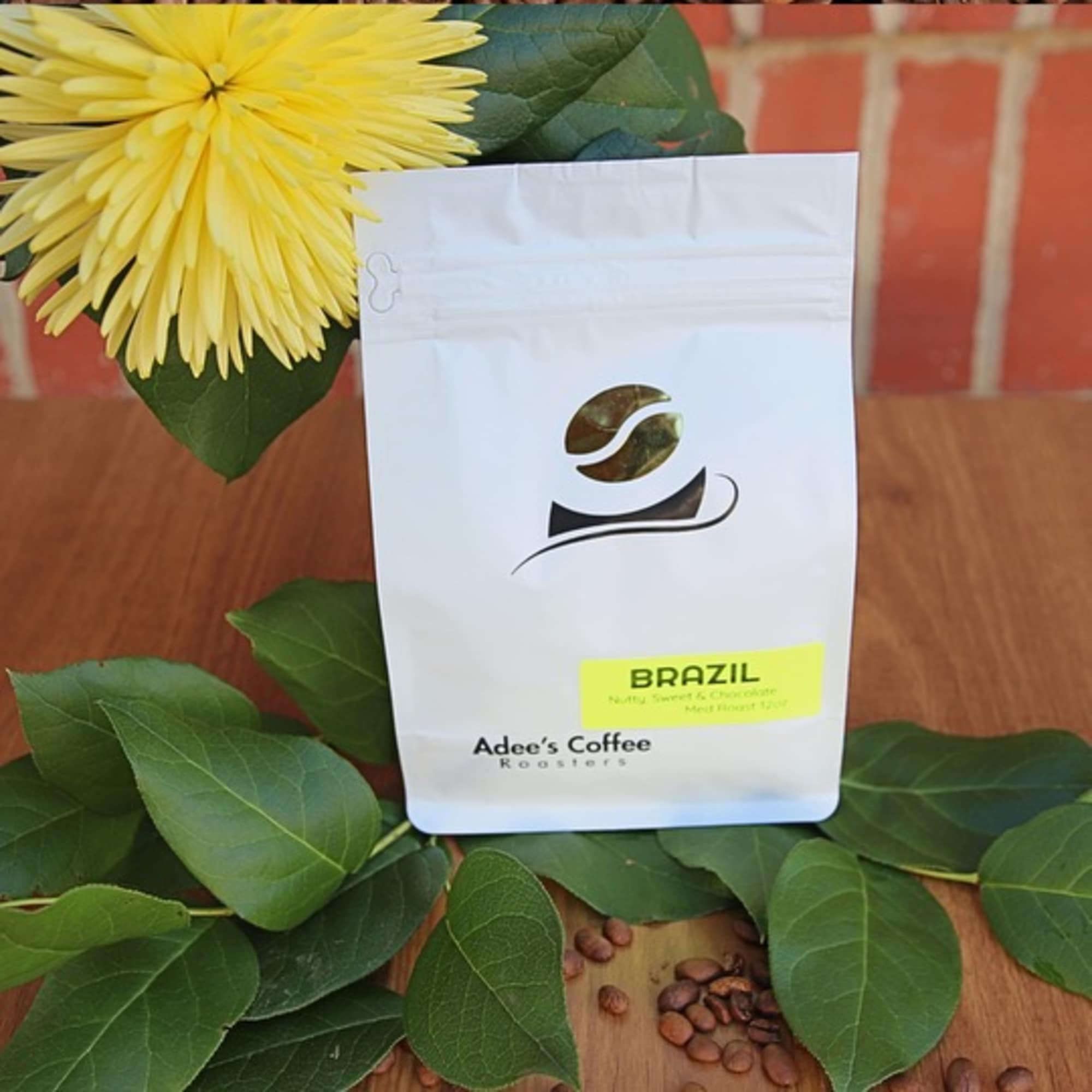 Yellow flower beside a white coffee bag with scattered beans
