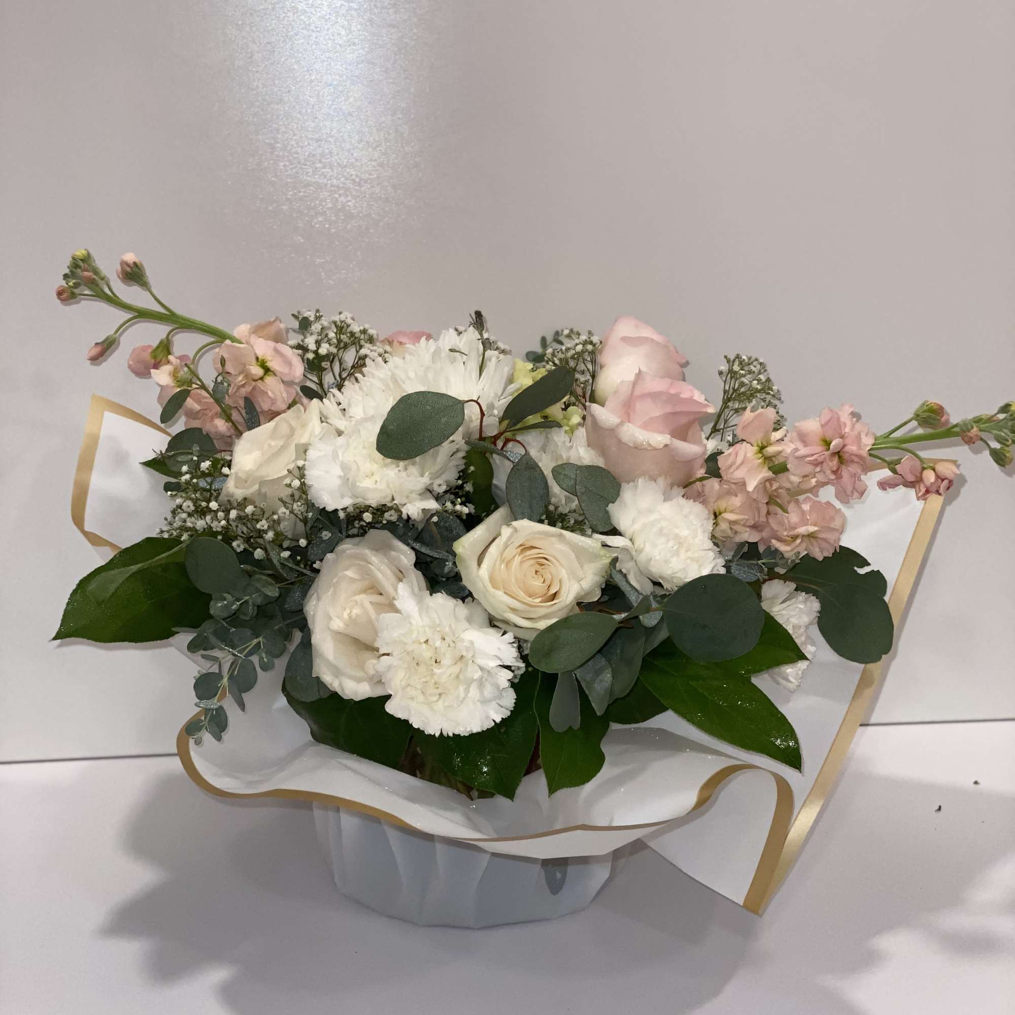 Bouquet of white and blush flowers in a wrapped container