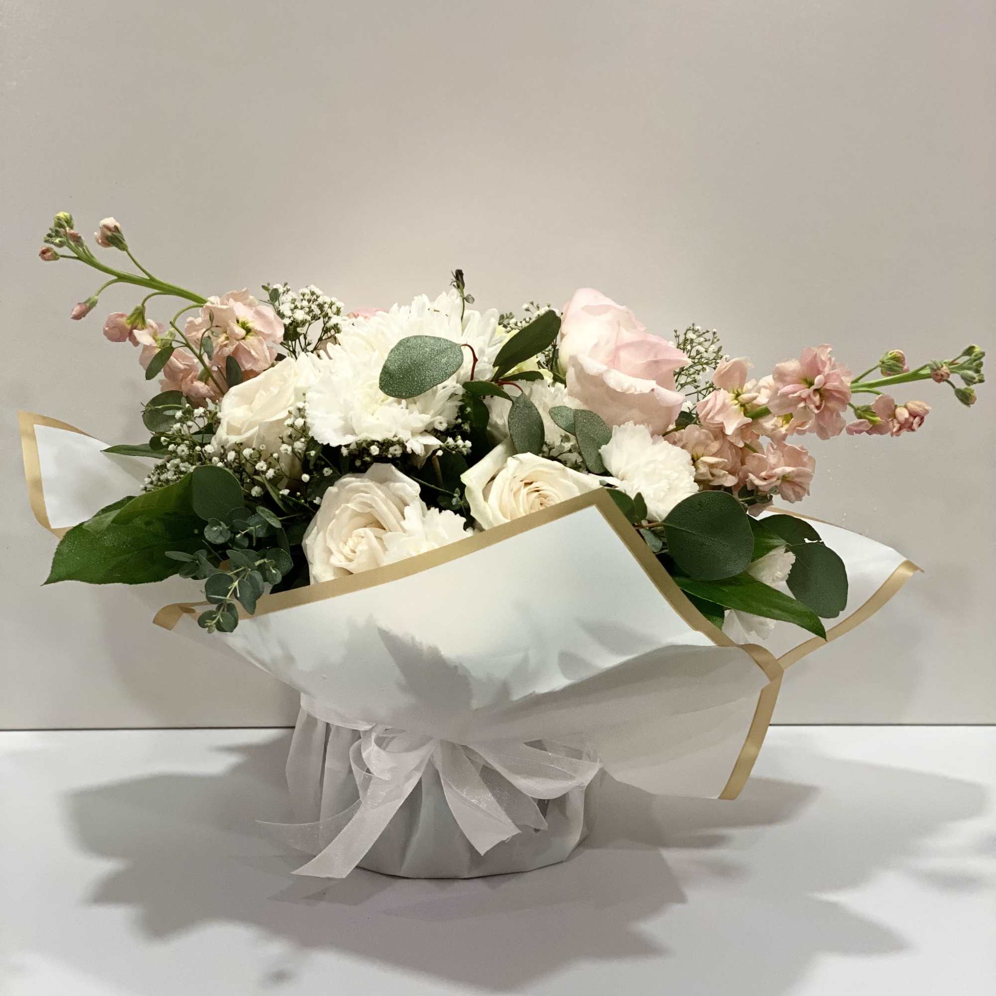 Pink and white bouquet in white wrapping with a ribbon
