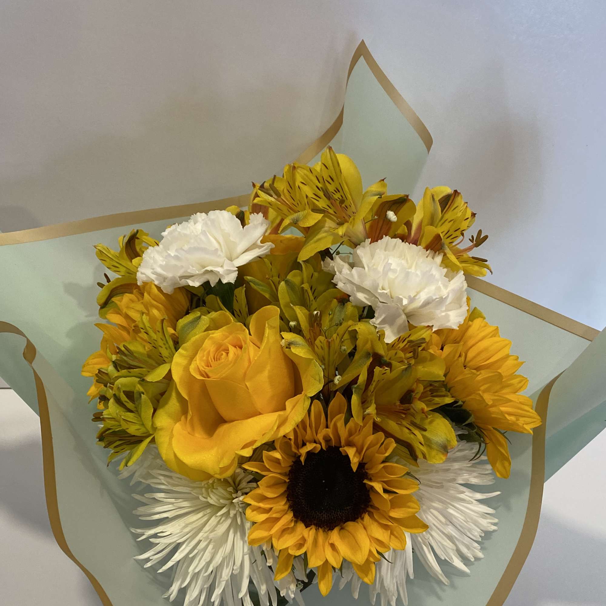Bouquet of yellow and white flowers wrapped in pale blue paper