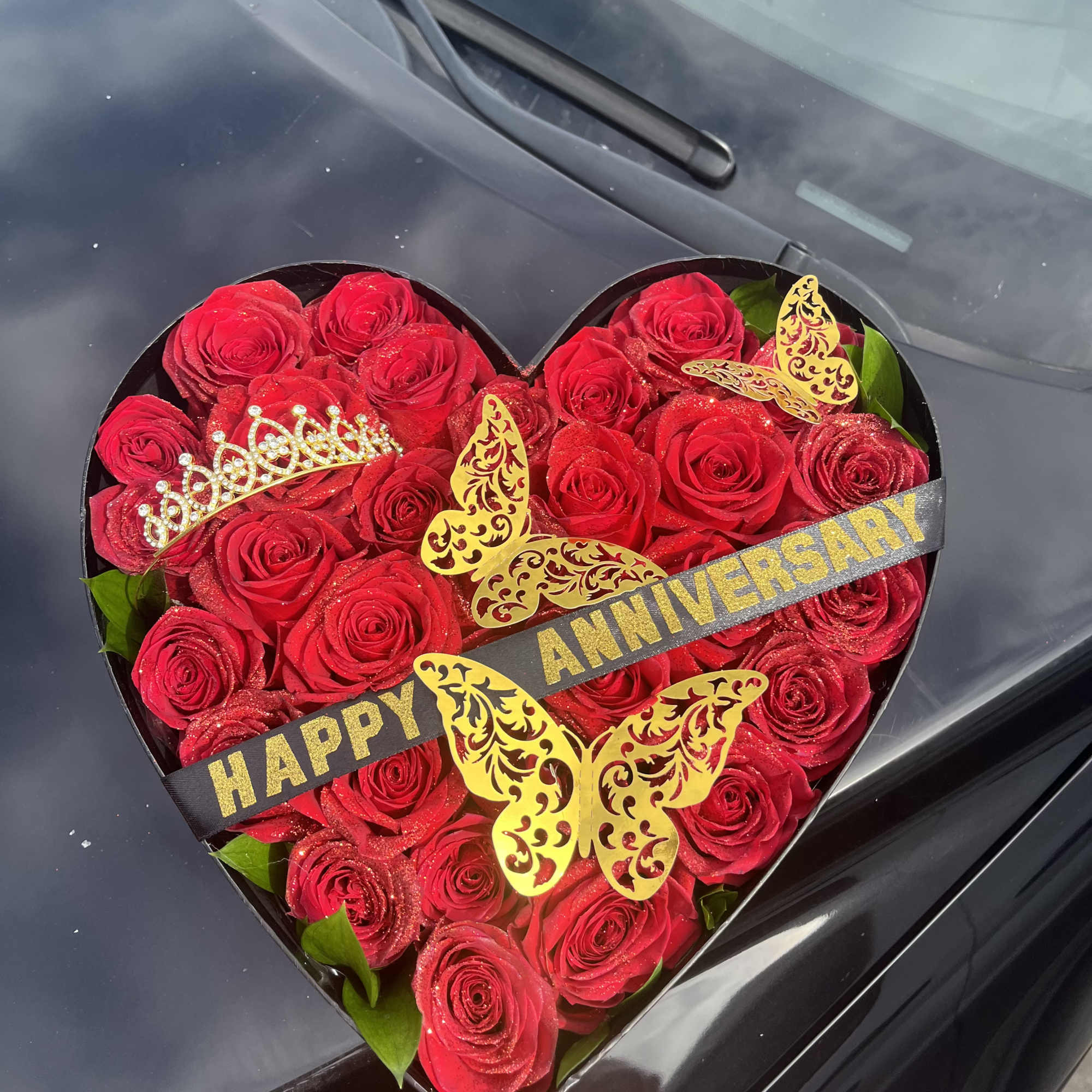 Heart-shaped box of red roses with anniversary ribbon and butterfly decorations