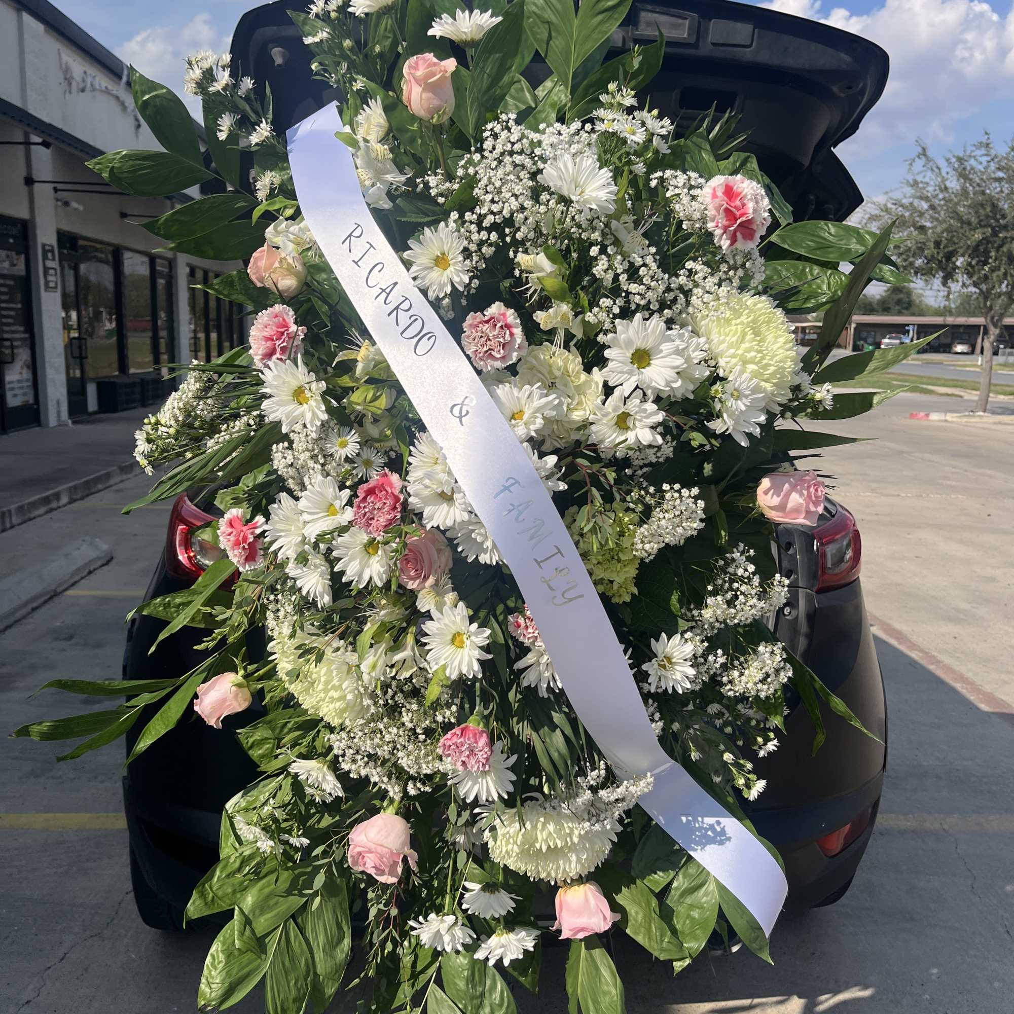 A soft, formal standing spray in white, pink, and green designed as