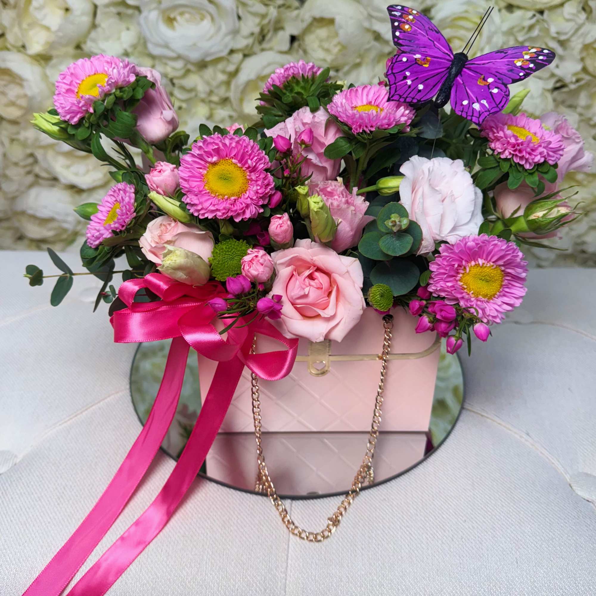 Pink and white flower arrangement in a blush box with a purple butterfly