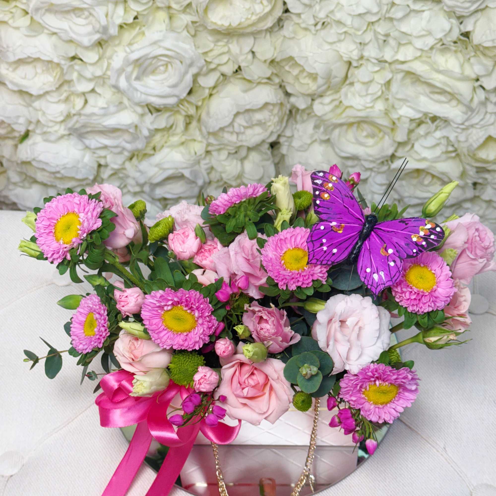 Pink and white bouquet in a round box with a purple butterfly decoration