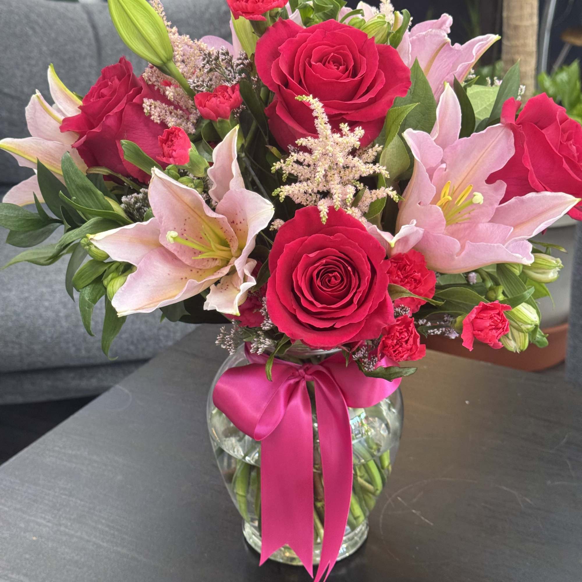 Pink roses and lilies in a glass vase with a ribbon