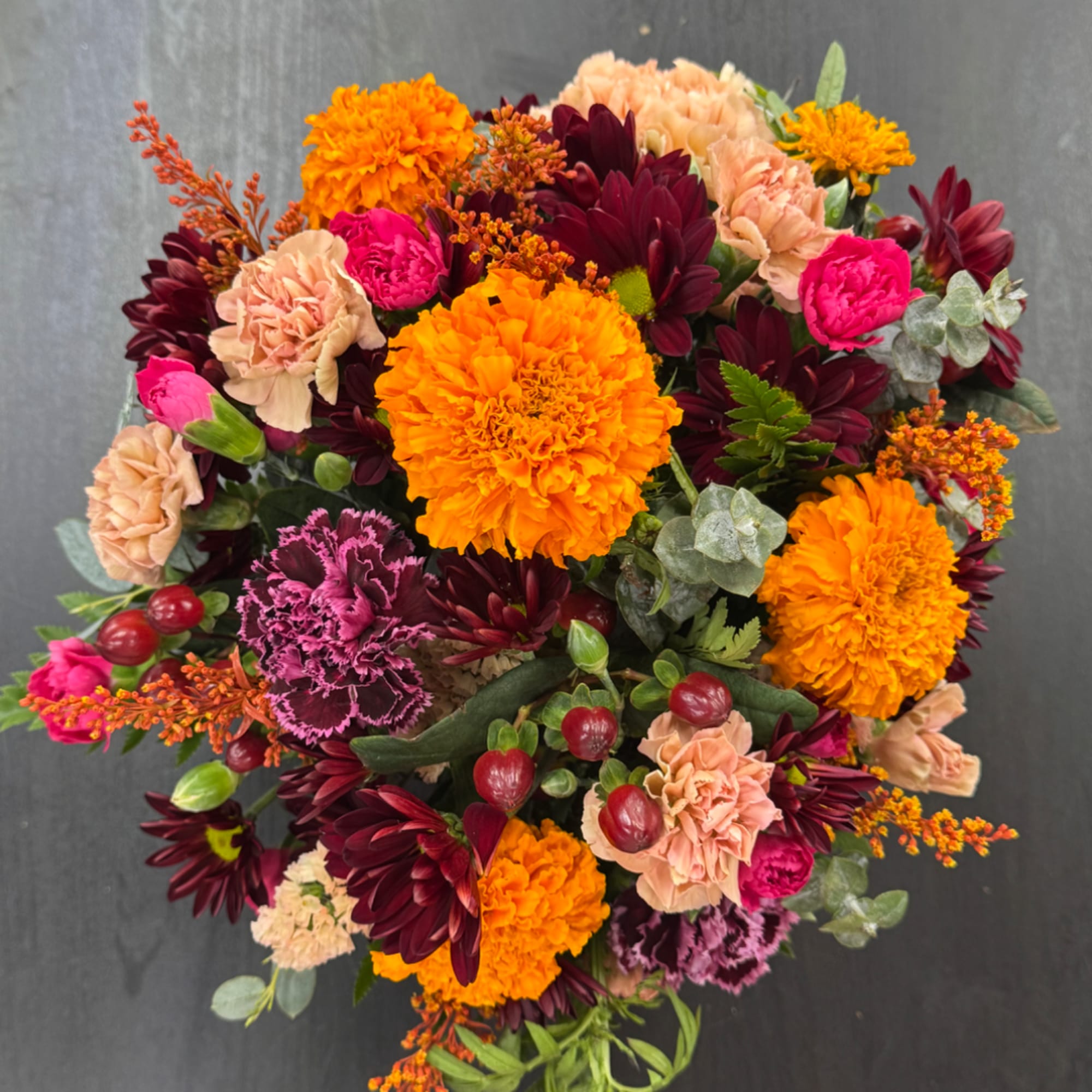 Colorful mixed bouquet with orange marigolds, burgundy daisies, and pink carnations