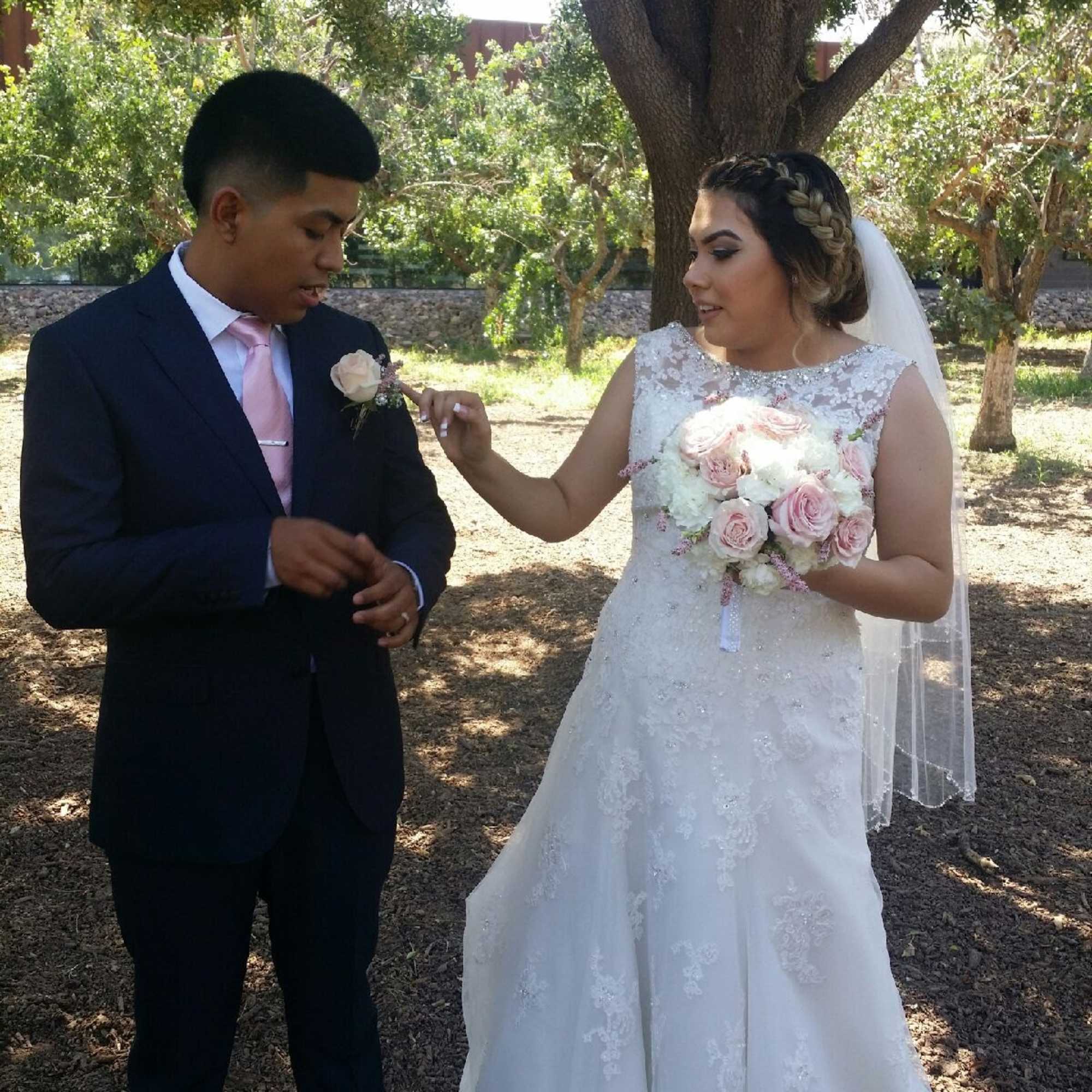 Bride holding a pink and white bouquet beside a groom with a boutonniere