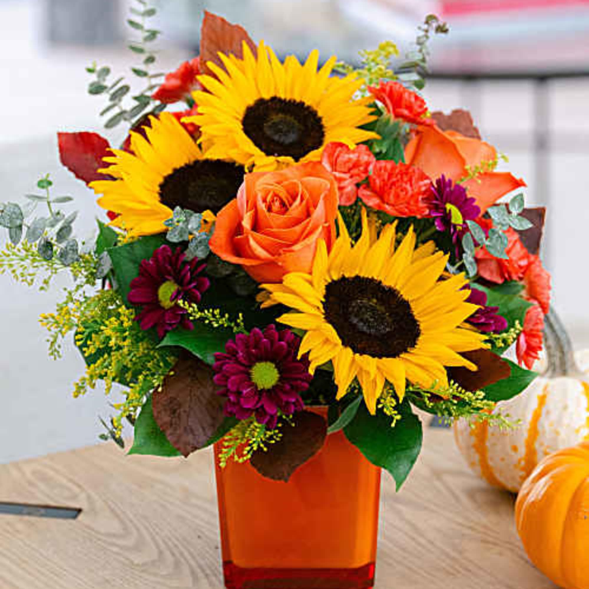 Sunflower and orange rose bouquet in a square orange vase