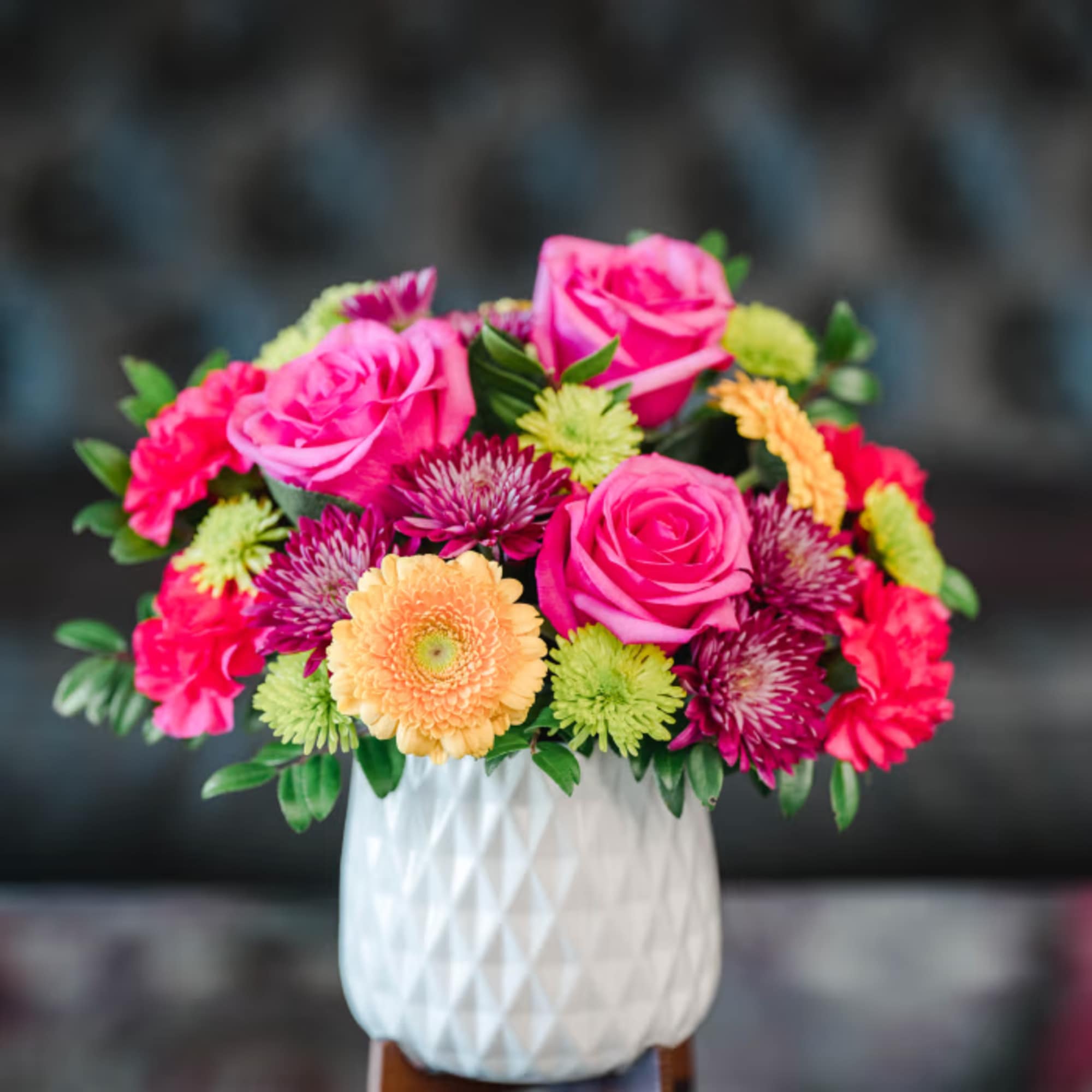 Pink roses and mixed chrysanthemums in a white vase
