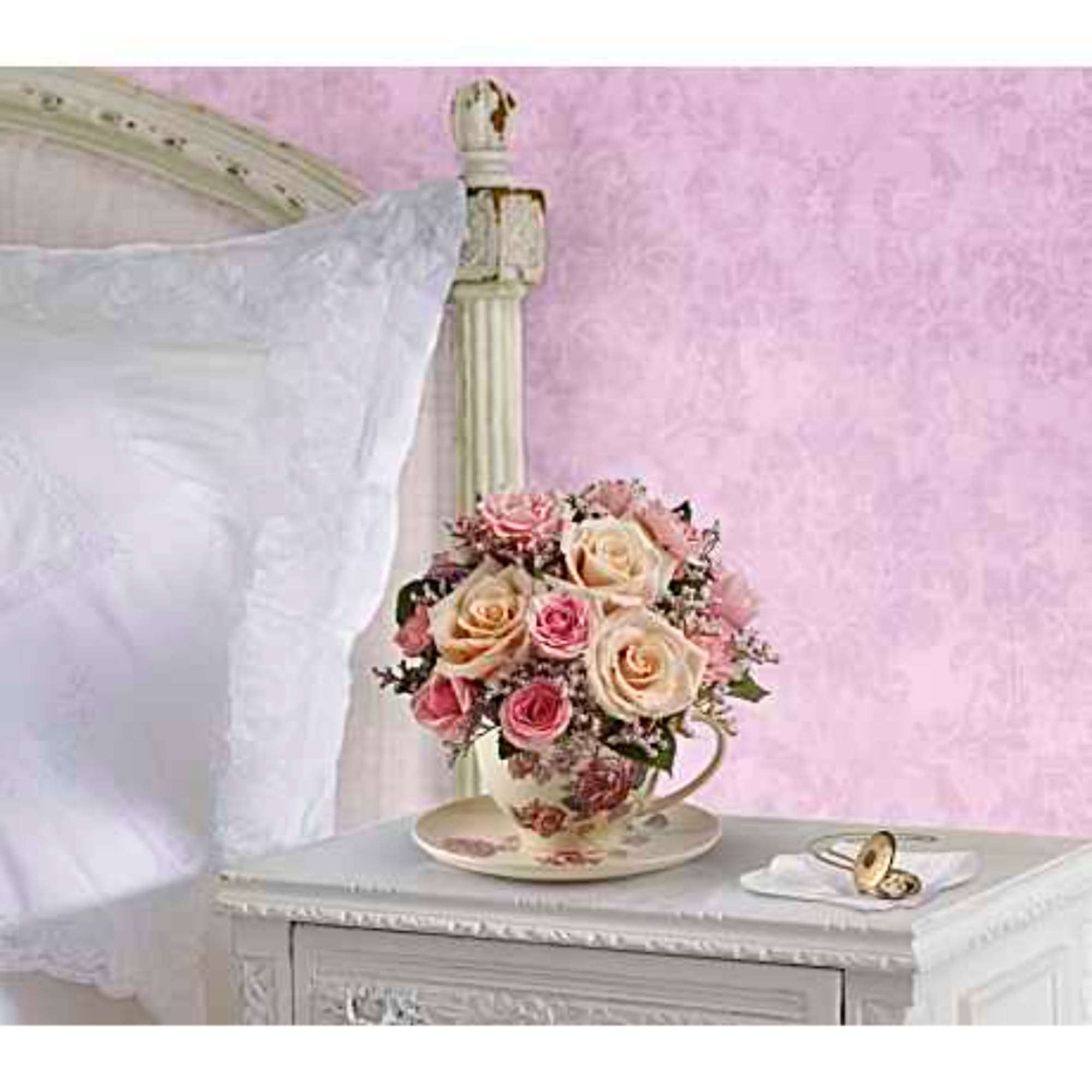 Pink and cream rose bouquet in a teacup on a bedside table