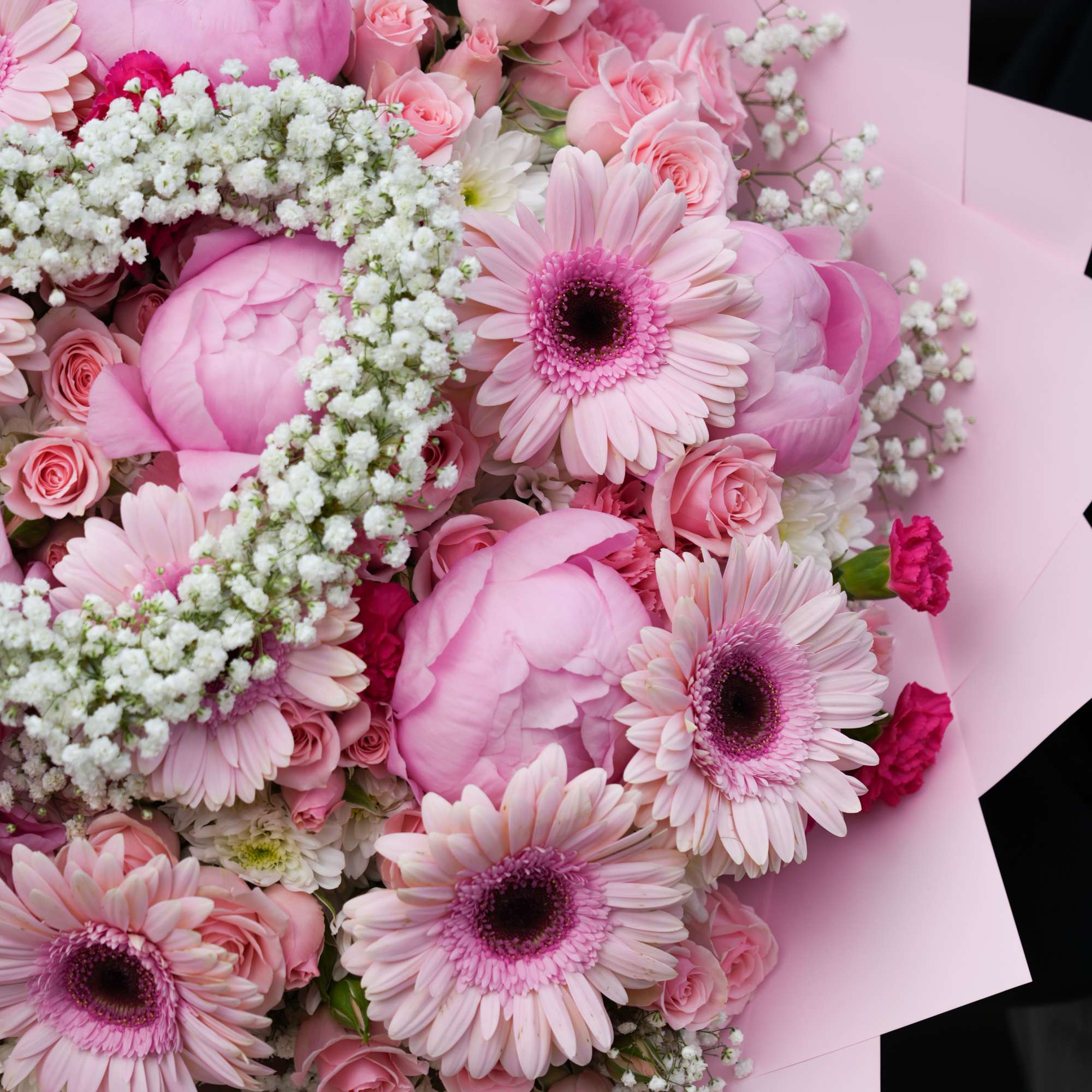 Pink bouquet with gerbera daisies, roses, and peonies wrapped in pastel paper