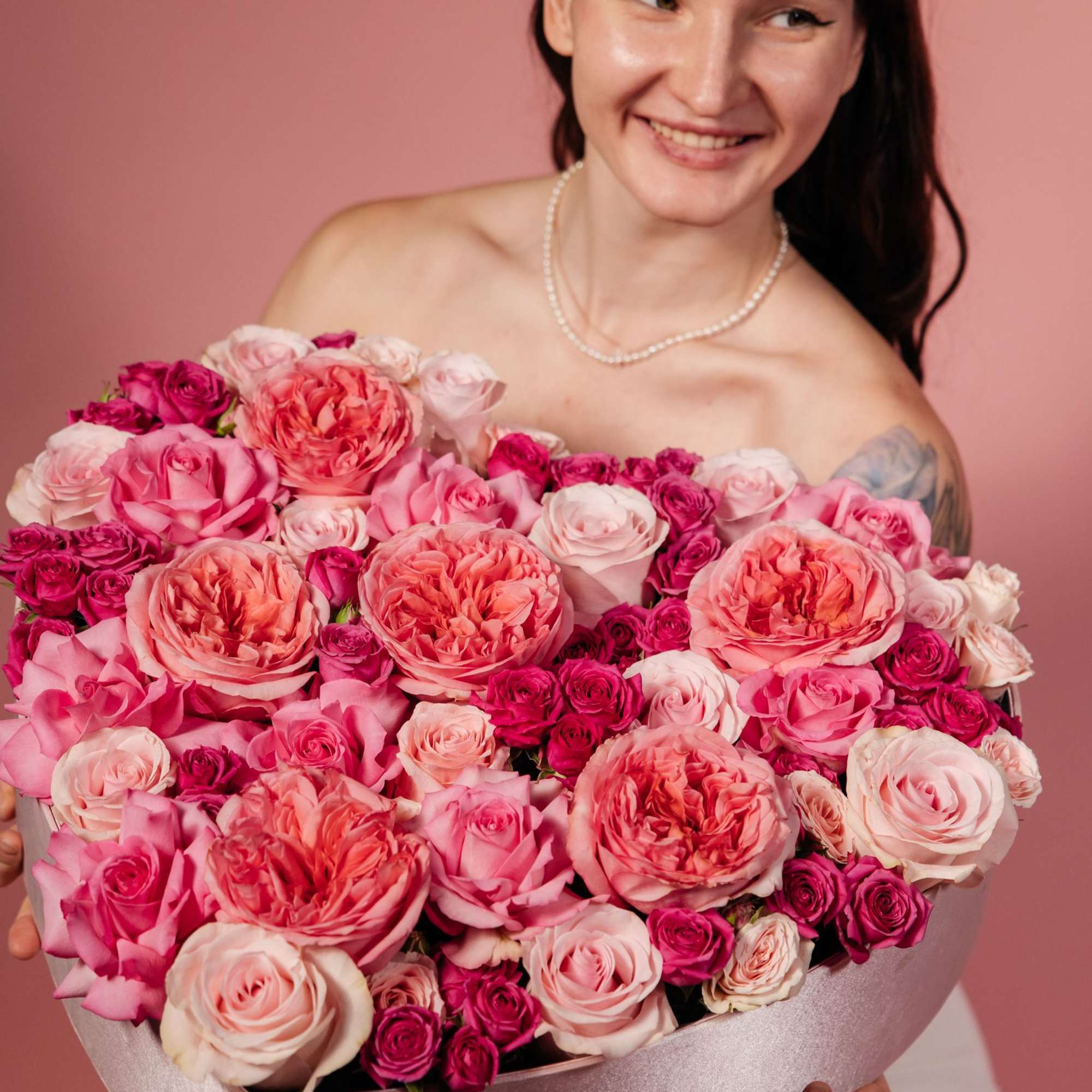 Woman holding a large pink rose bouquet in a box