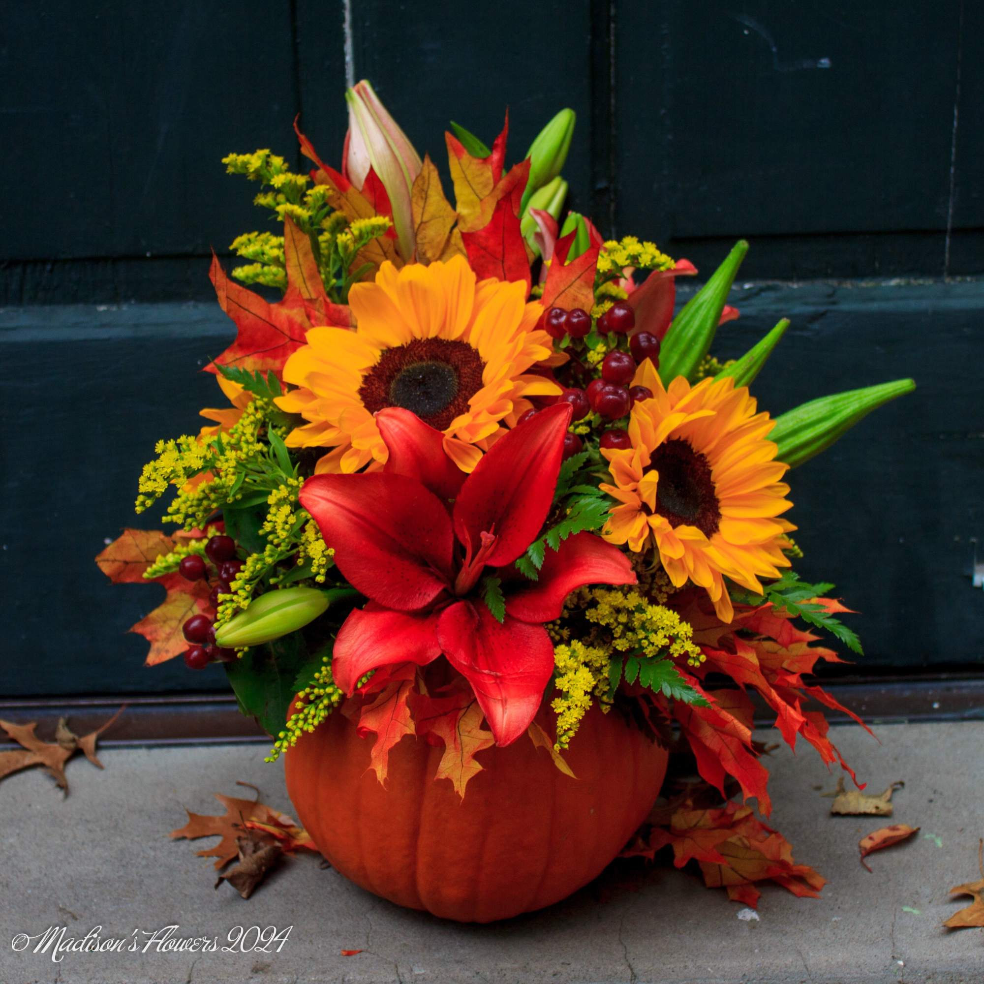 Autumn floral arrangement in a pumpkin container with sunflowers and red lilies