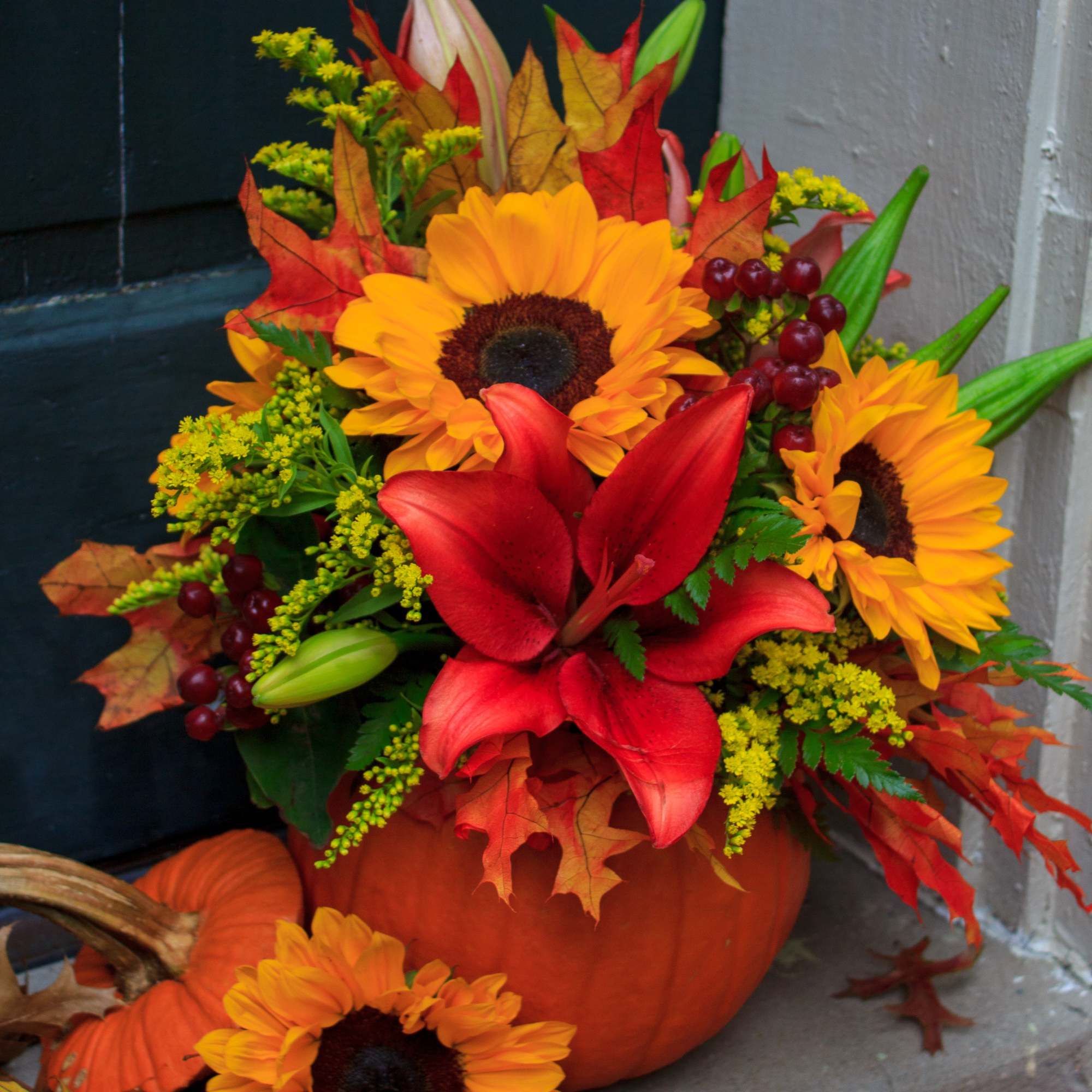 Pumpkin arrangement with sunflowers and red lilies