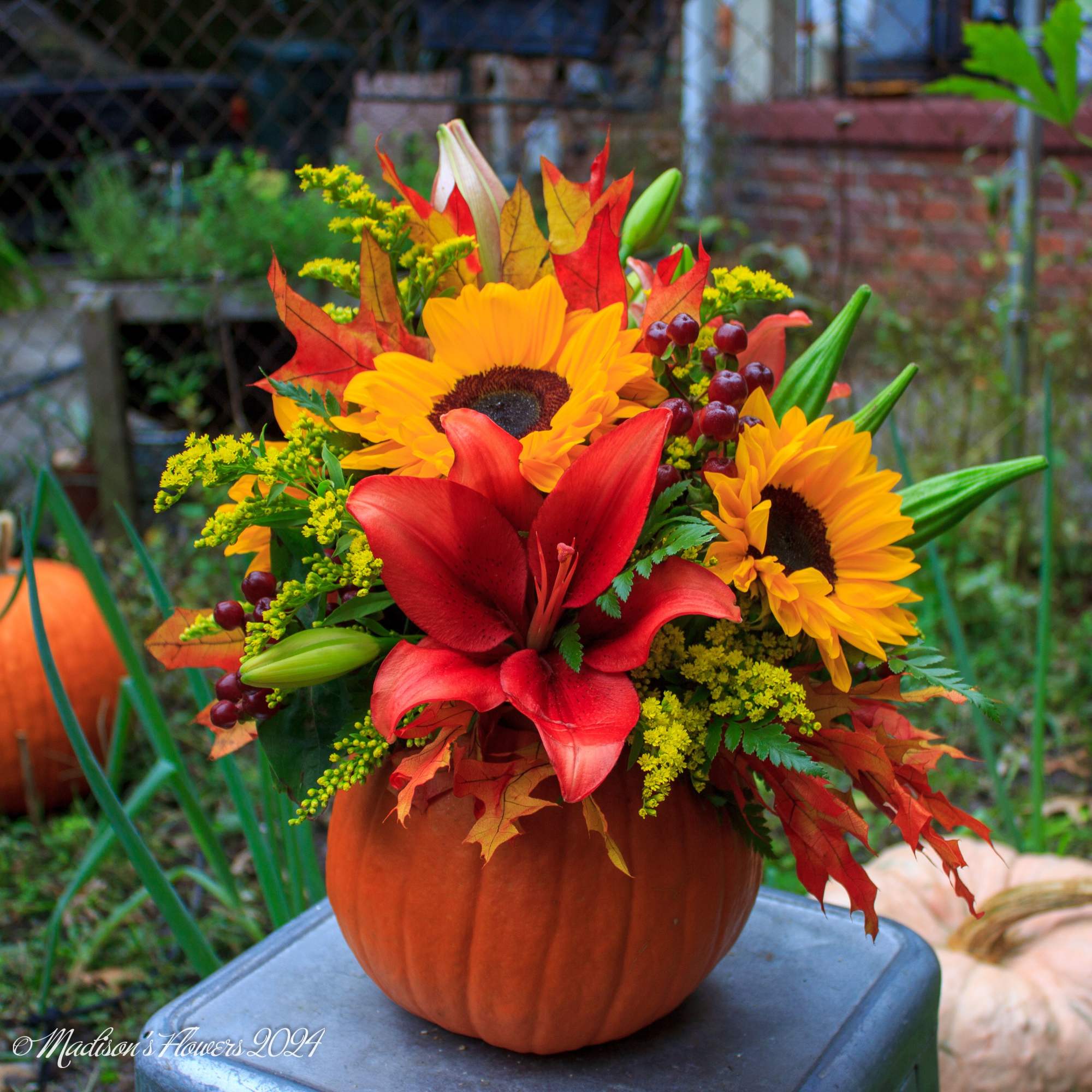 Autumn floral arrangement in a pumpkin container with sunflowers and red lilies, photo 4 of 5