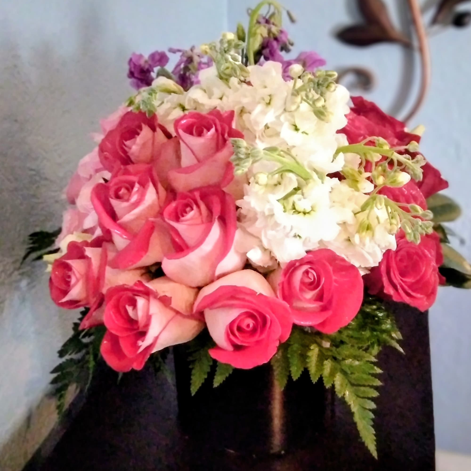 Bouquet of pink and white roses with purple accents in a vase