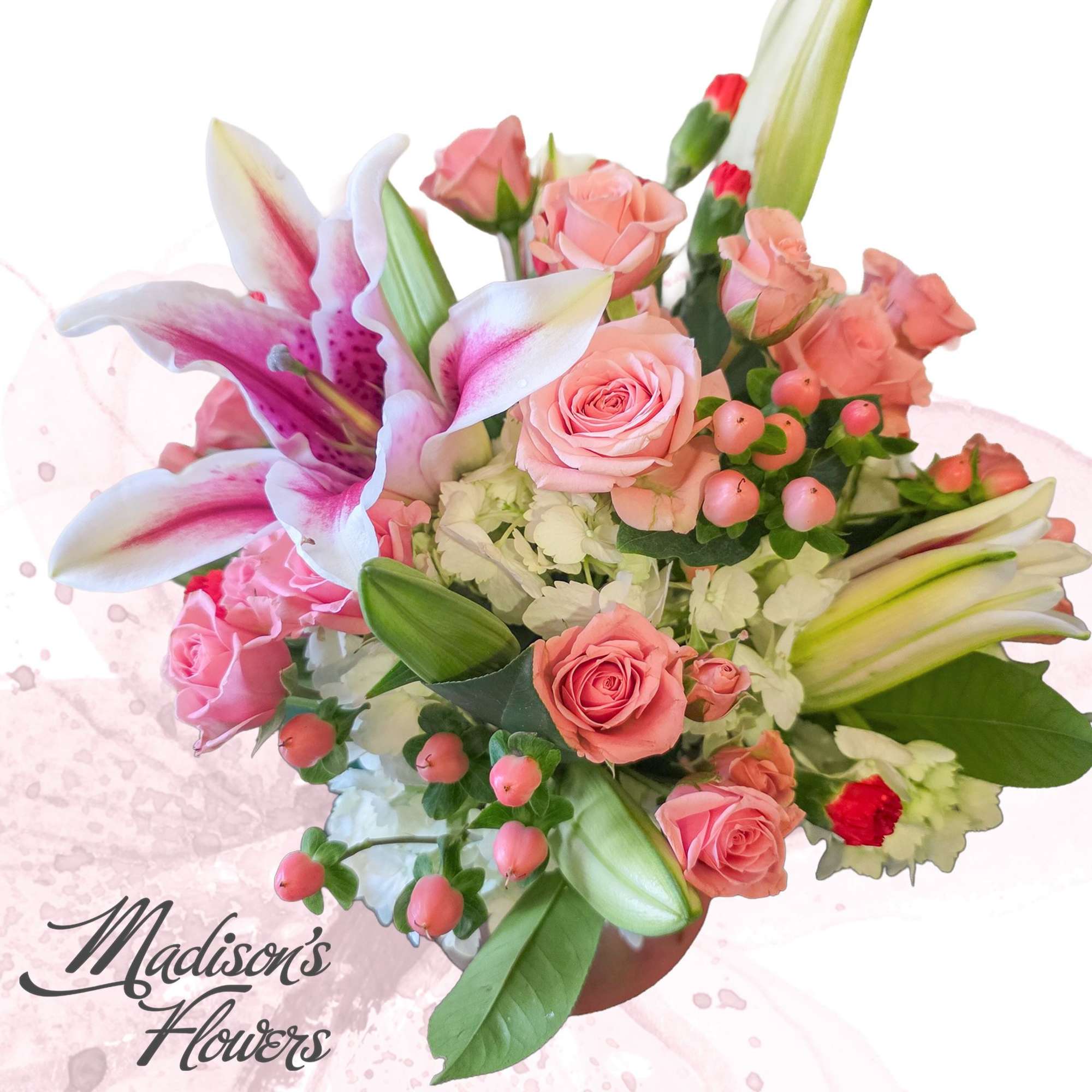 Pink lilies and roses with white hydrangea and berries arranged in a vase