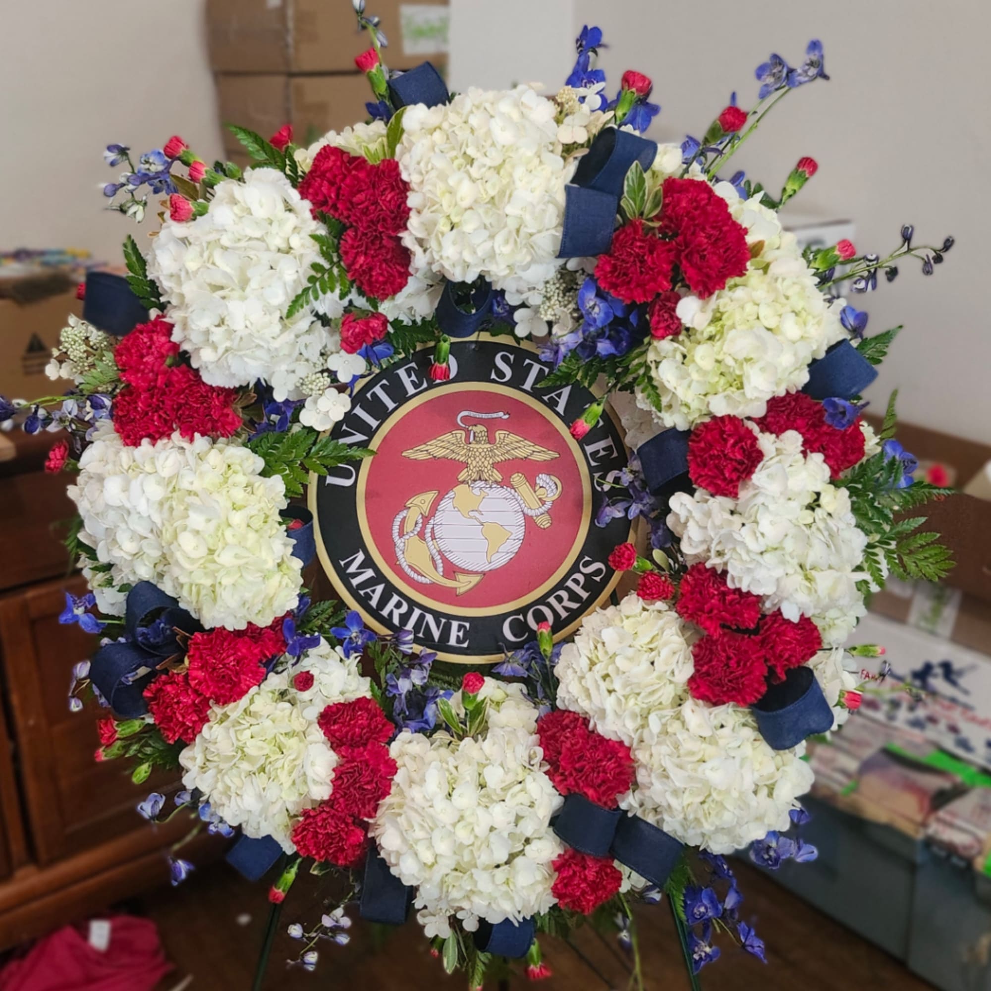 Floral wreath with white and red carnations around a U.S. Marine Corps emblem