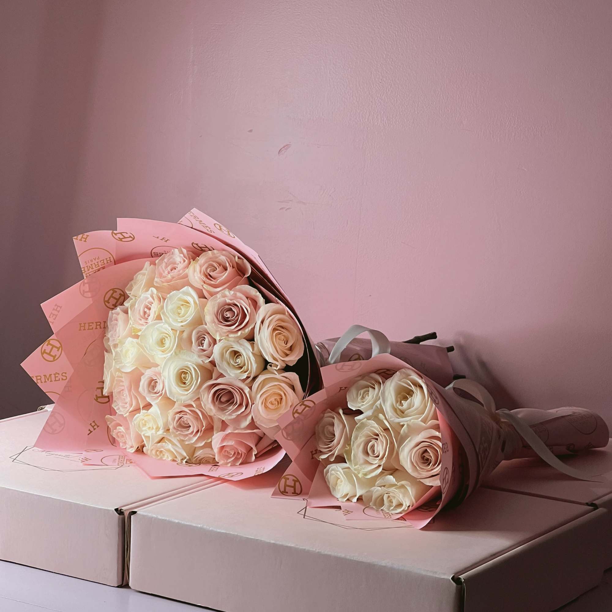 Two bouquets of pale pink and white roses wrapped in pink paper