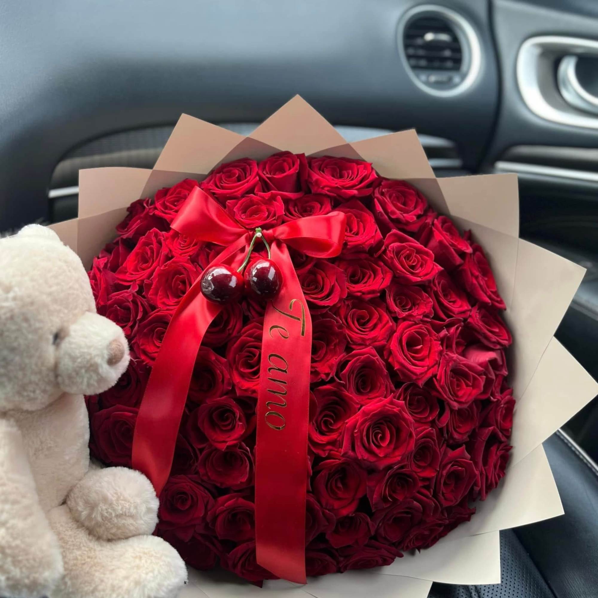 Round bouquet of red roses with a red ribbon and teddy bear