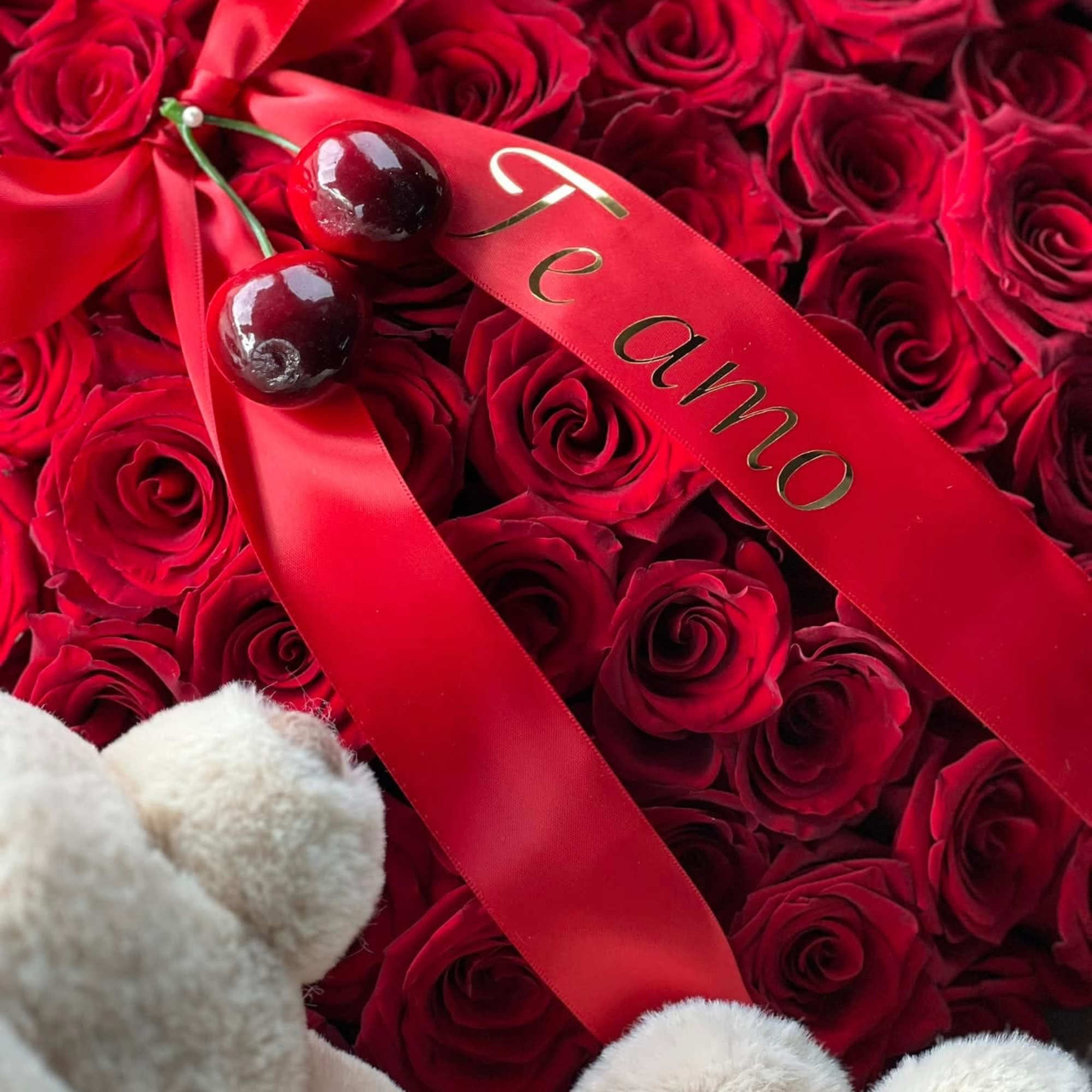 Red rose arrangement with a red ribbon and plush teddy bear