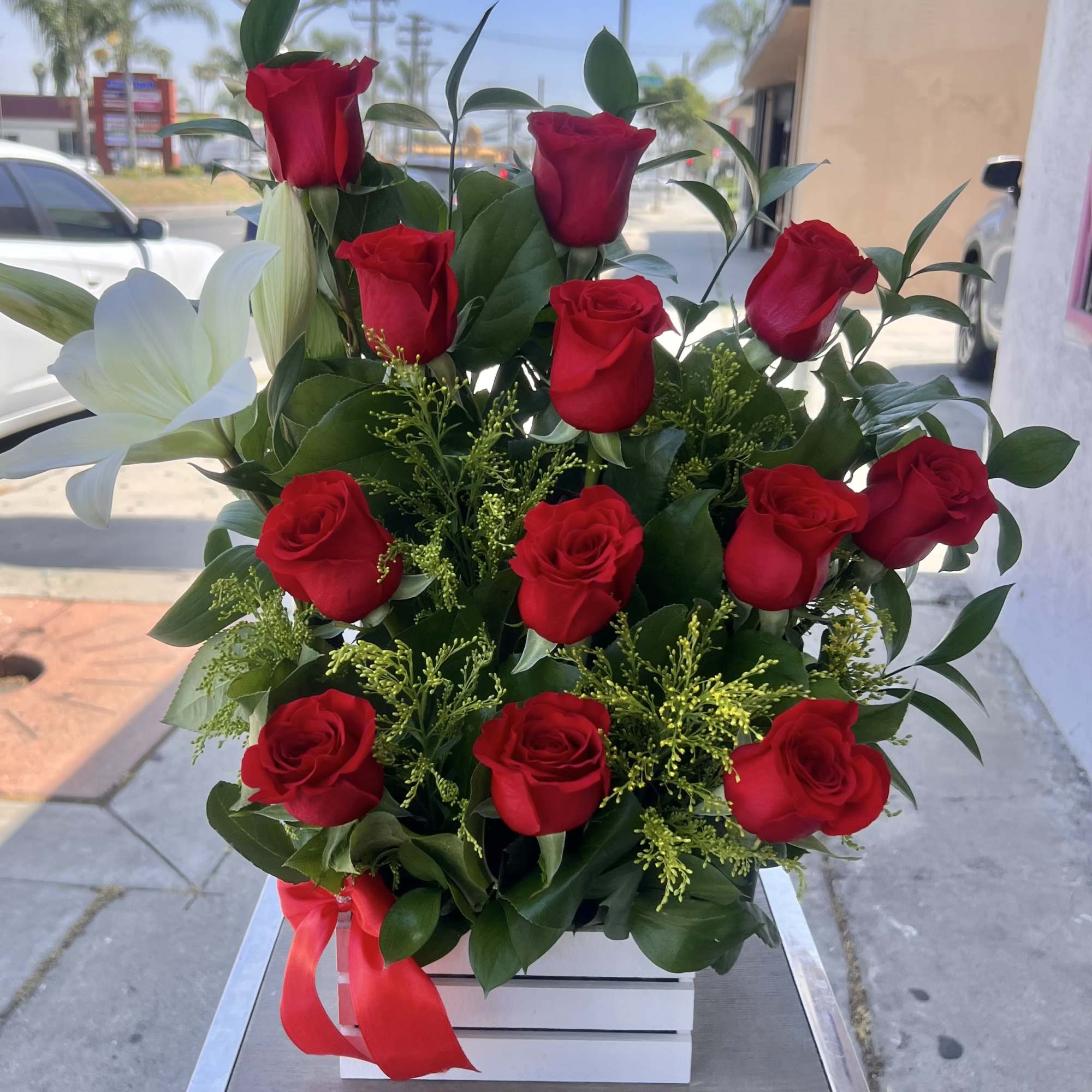 Red roses arranged in a white box with a red ribbon