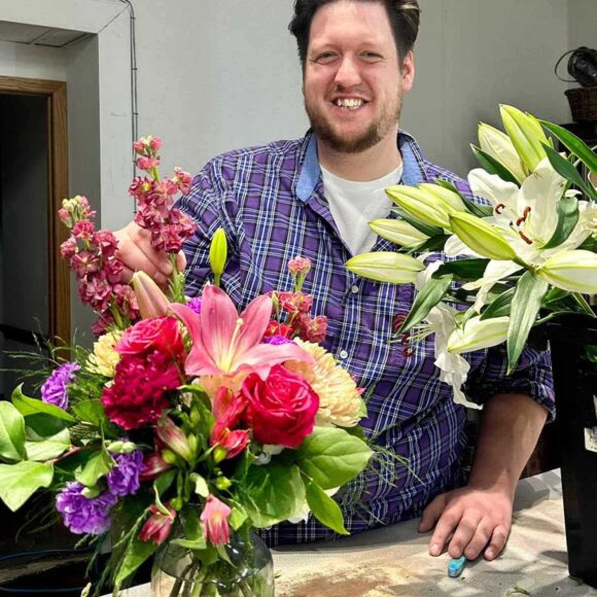 Two colorful flower arrangements with lilies, roses, and purple blooms on a table
