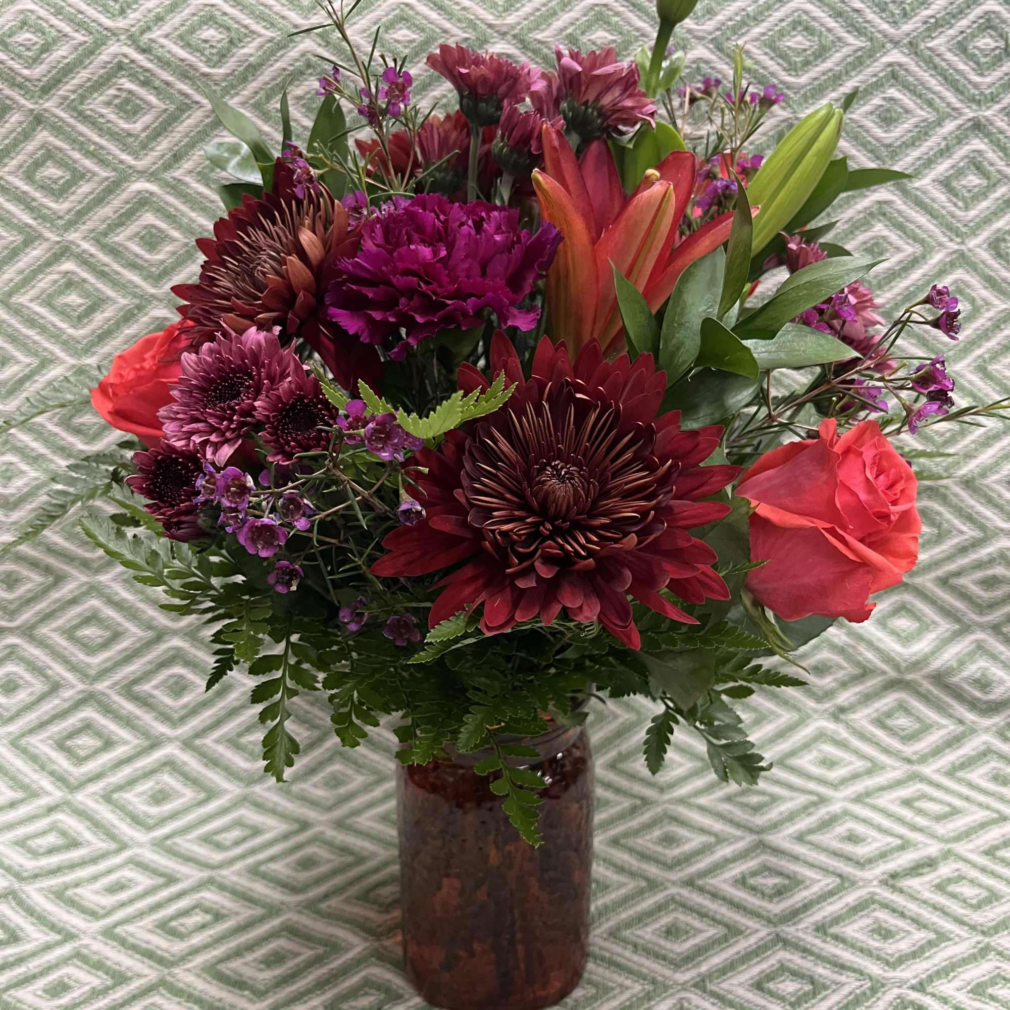 Mixed bouquet of burgundy and pink flowers in a glass vase