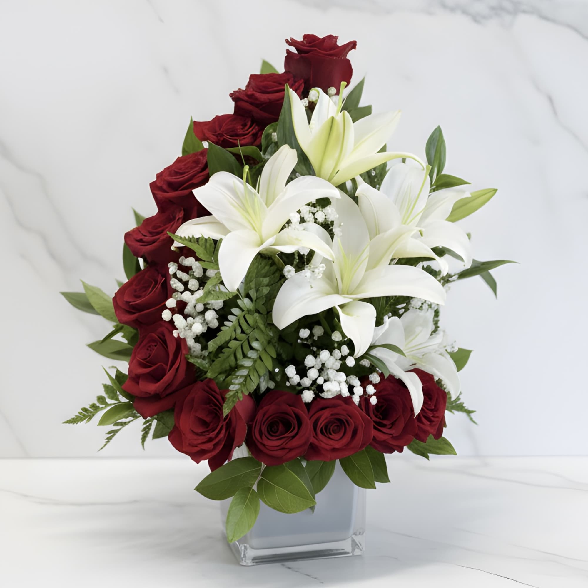 Red roses and white lilies arranged in a clear square vase