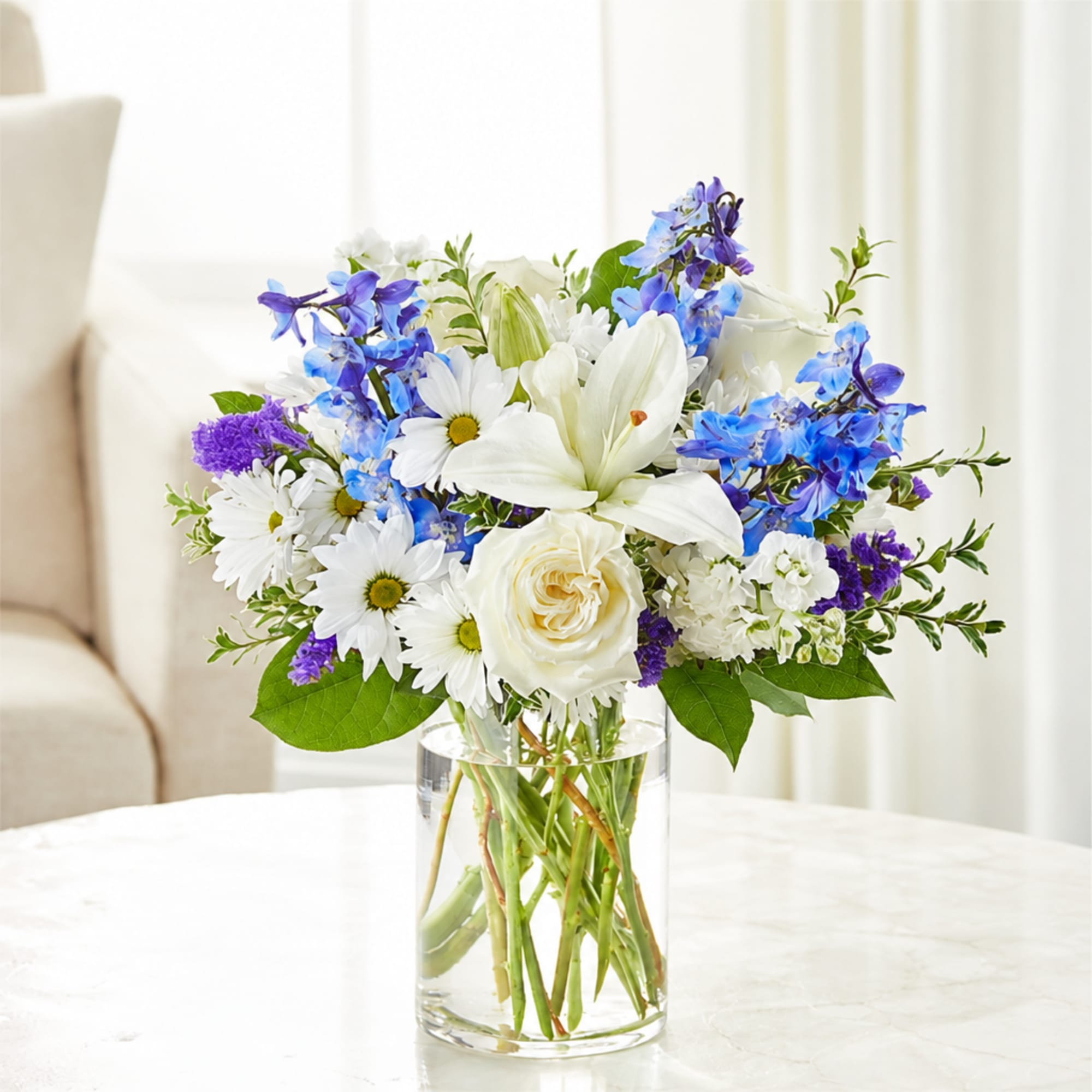 White and blue mixed bouquet in a clear glass vase