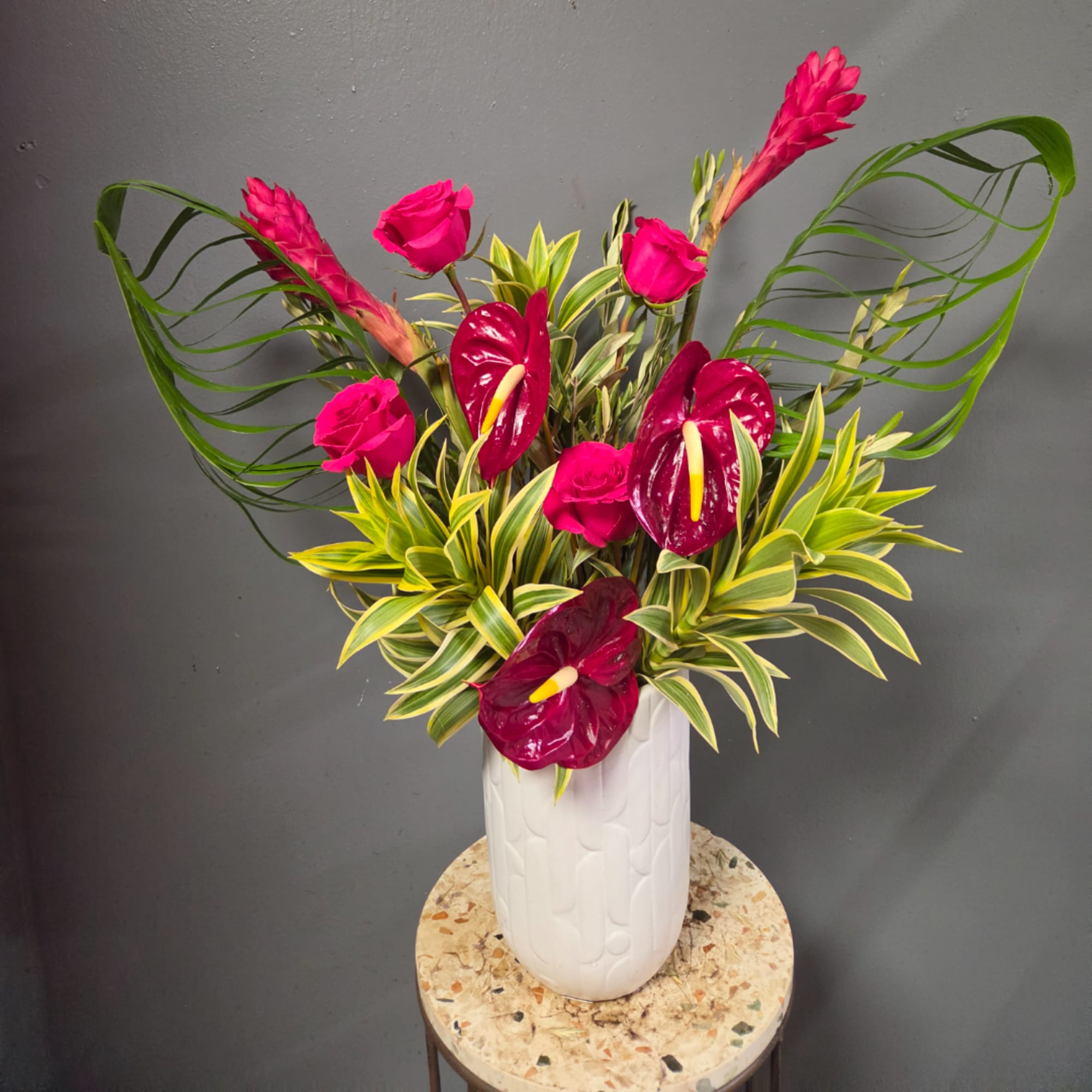 Pink roses and burgundy anthuriums in a white vase