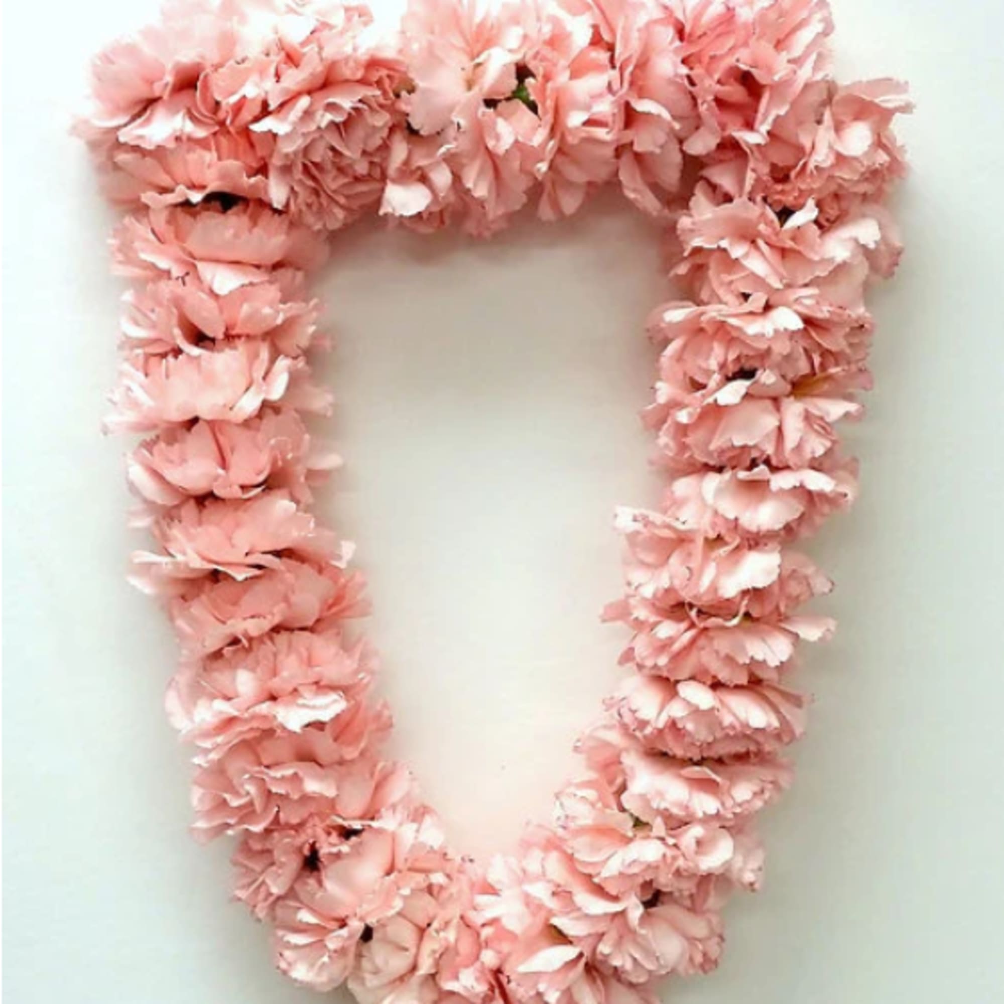 Pink flower garland arranged in a U shape on a white background