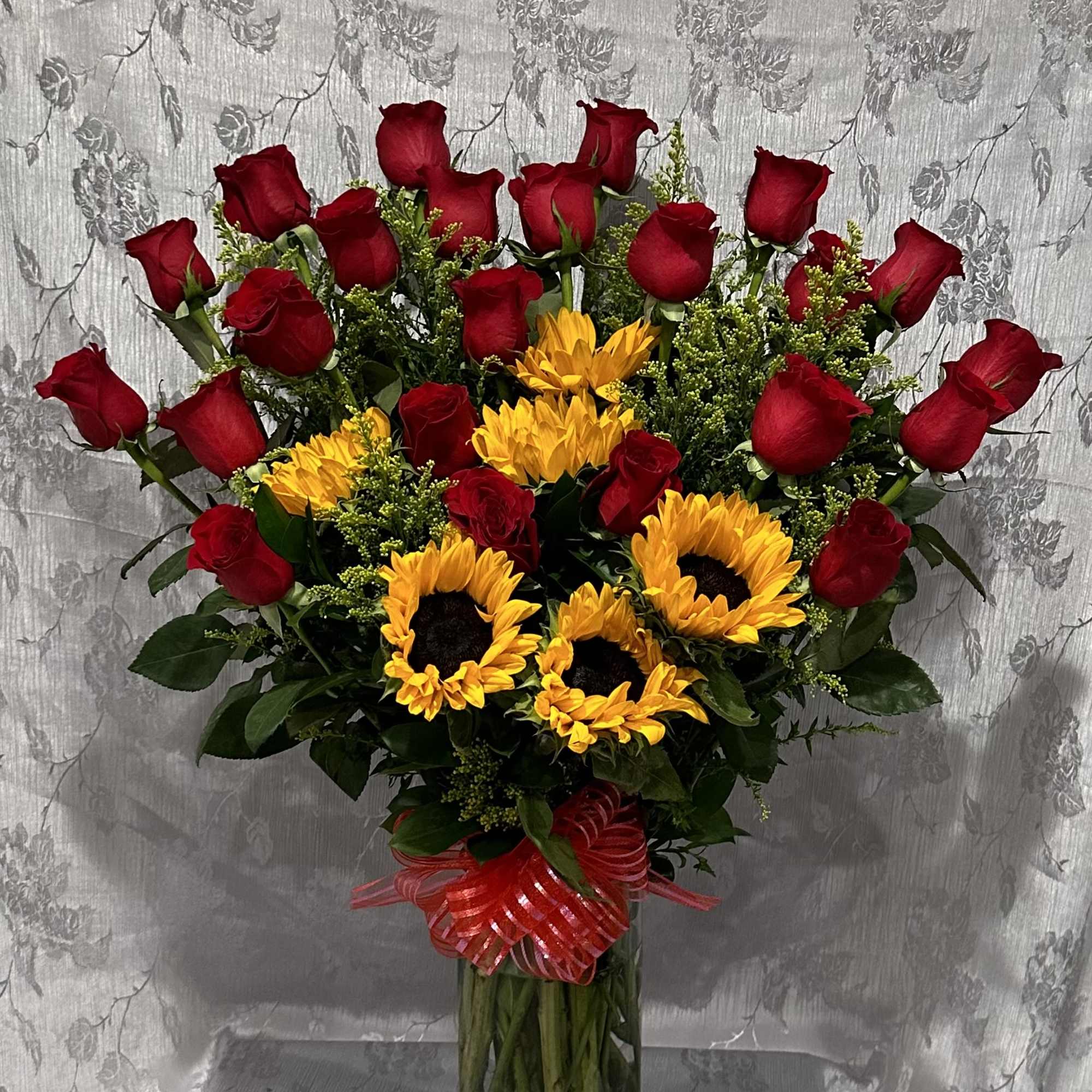 Bouquet of red roses and yellow sunflowers in a glass vase