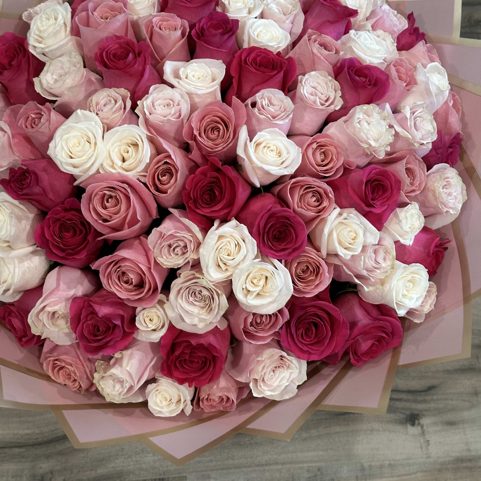 Large bouquet of pink, white, and red roses wrapped in pink paper