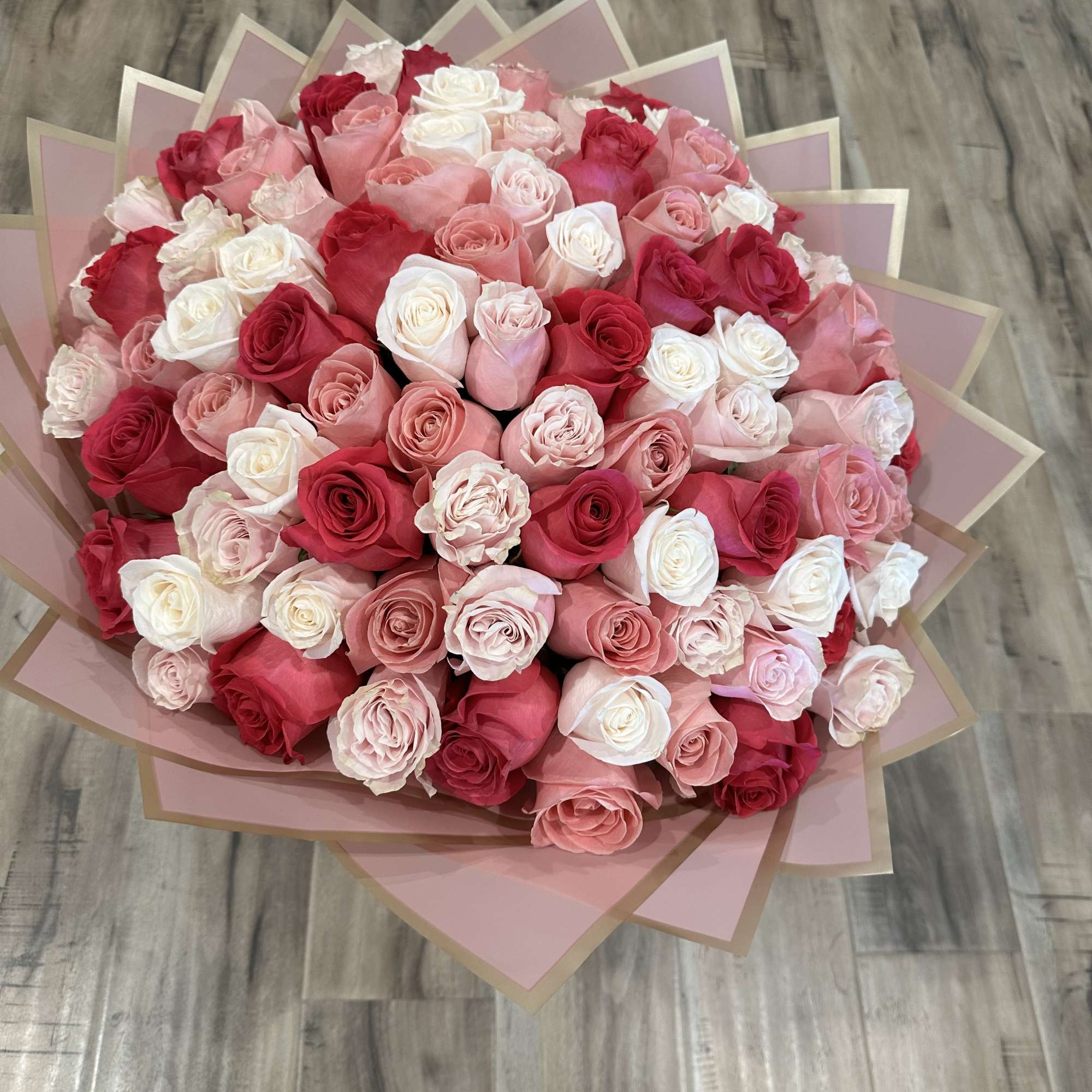 Large bouquet of pink, red, and white roses wrapped in pink paper, photo 3 of 3
