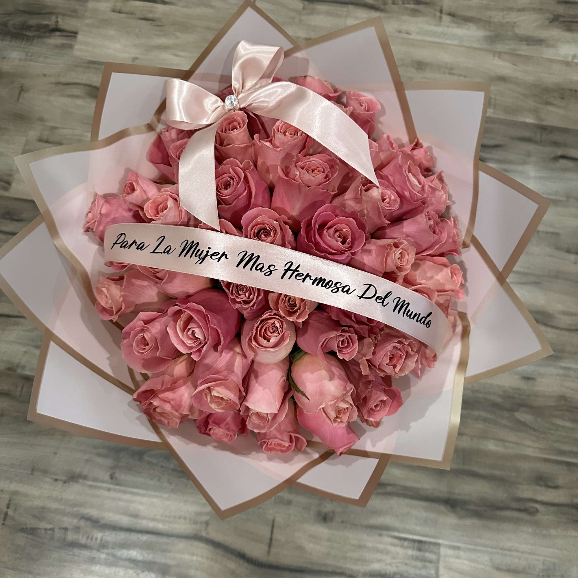 Pink rose bouquet wrapped in pale paper with a satin bow
