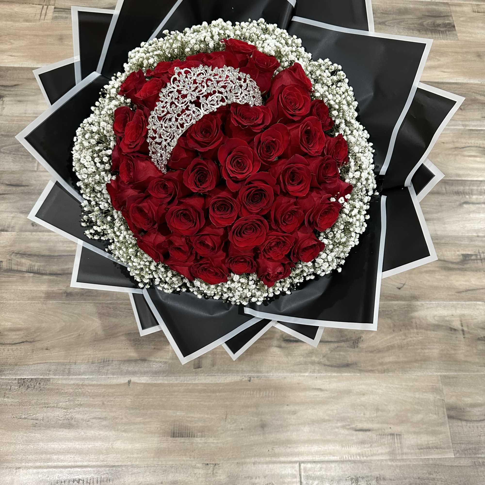 Round bouquet of red roses with white baby's breath and black wrapping