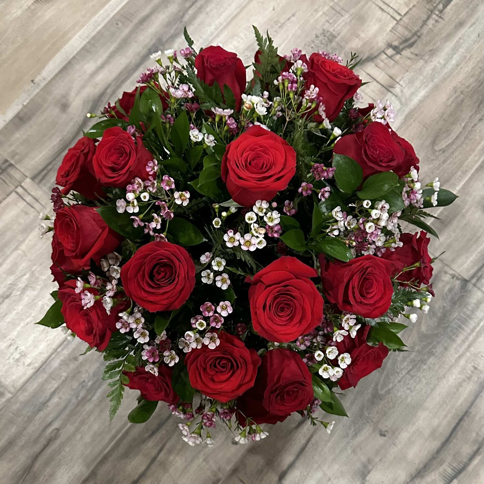 Round bouquet of red roses with small pink and white filler flowers