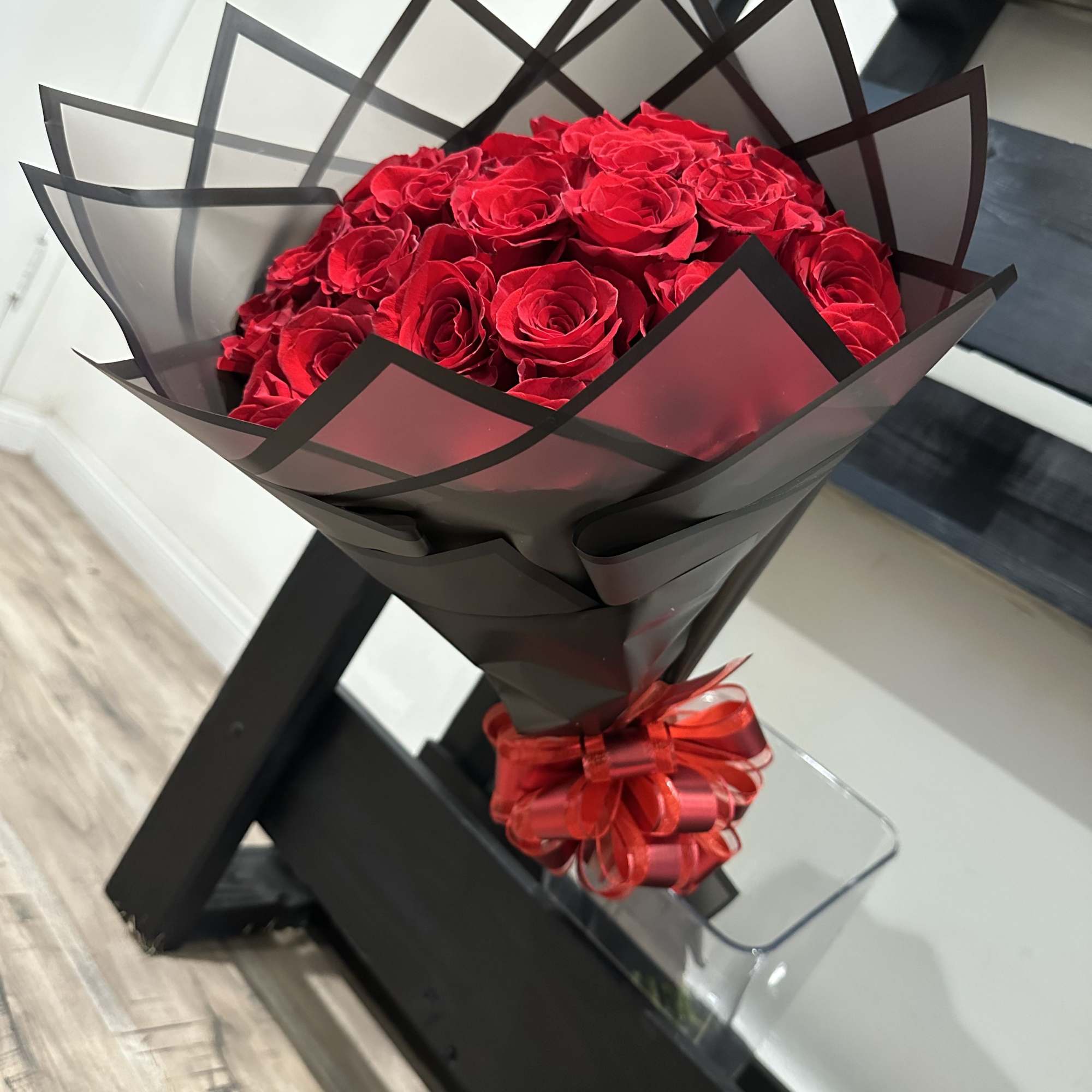 Bouquet of red roses wrapped in black paper with a red ribbon