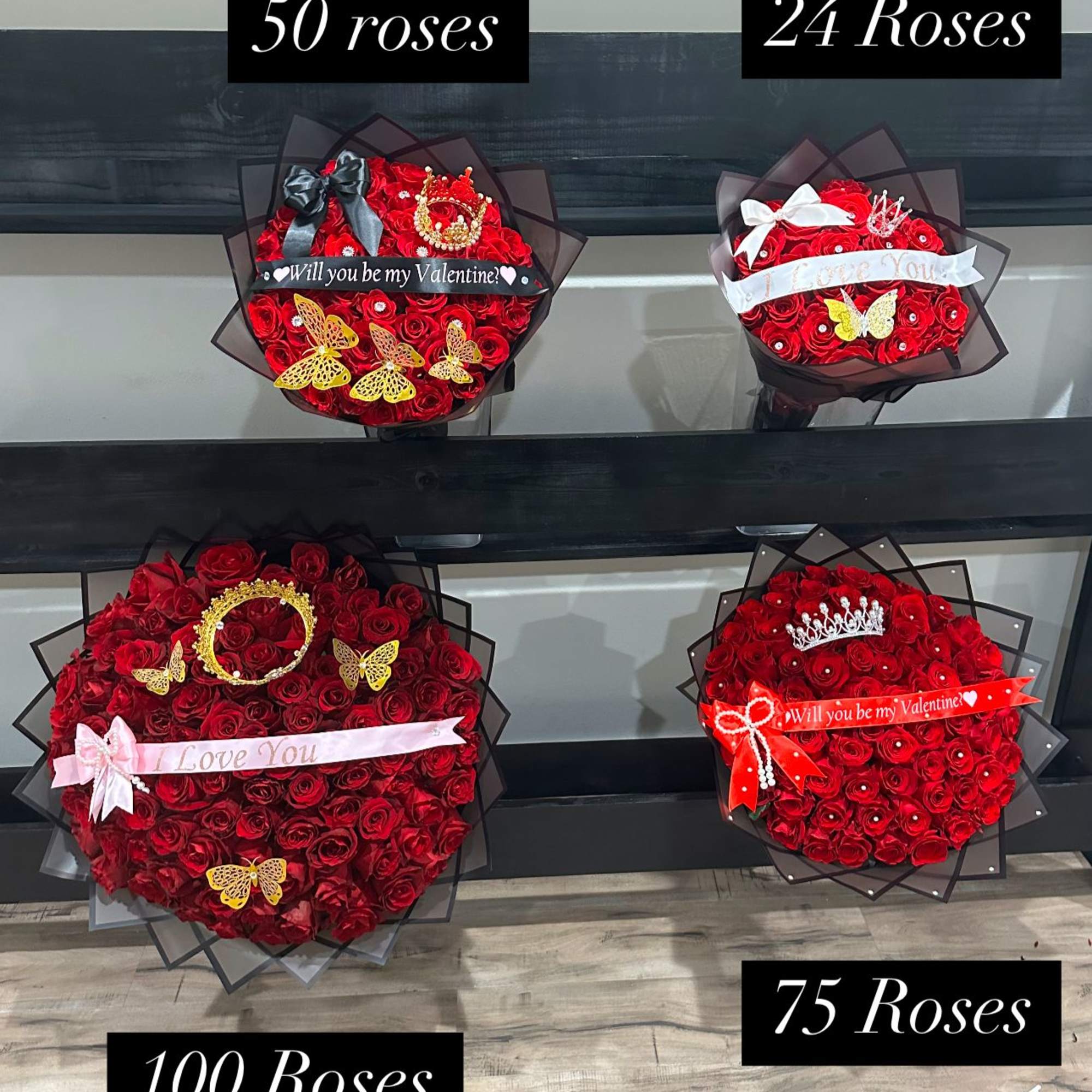 Four red rose bouquets with ribbons and butterfly decorations on display shelves.