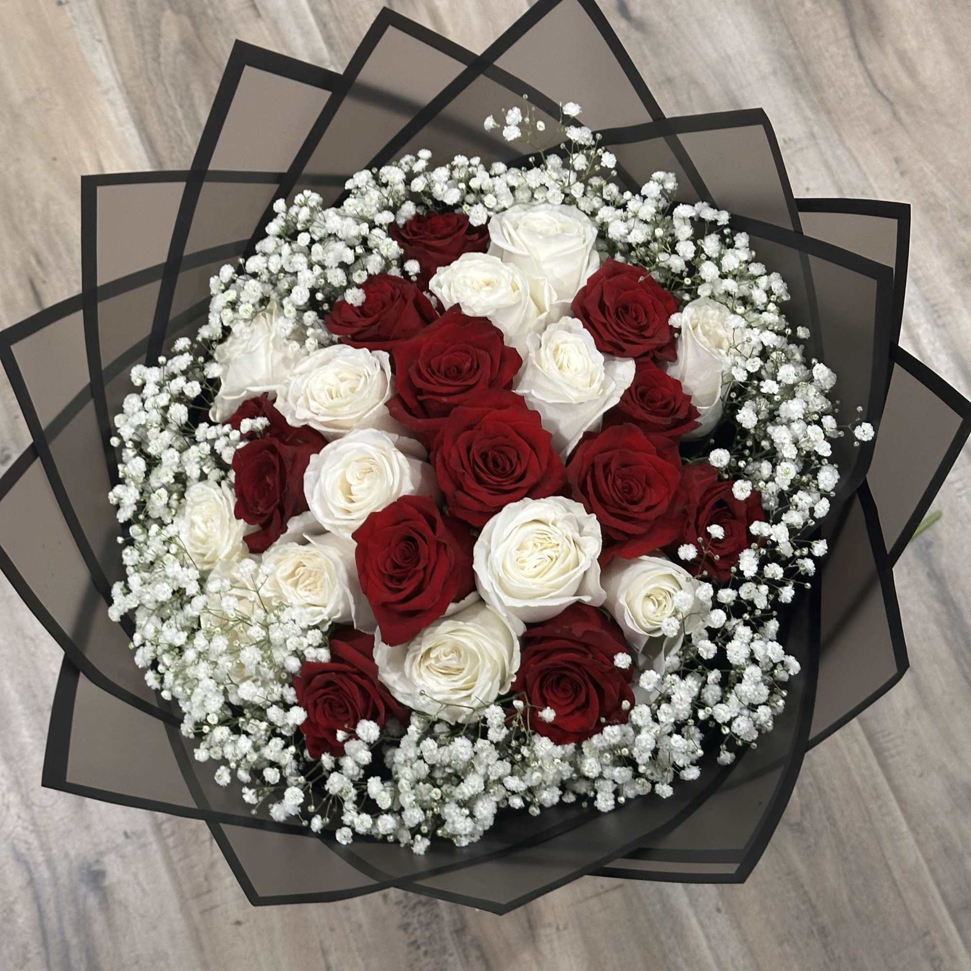 Bouquet of red and white roses with baby's breath in black wrap