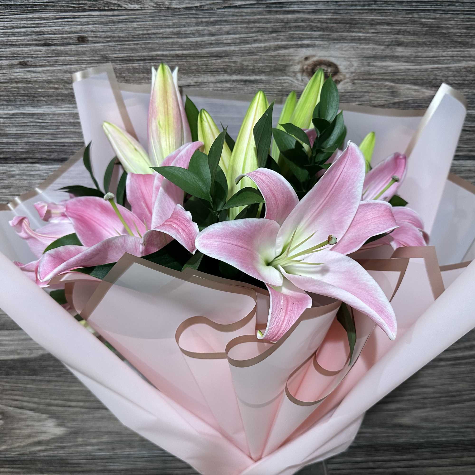 Bouquet of pink lilies wrapped in pale pink paper