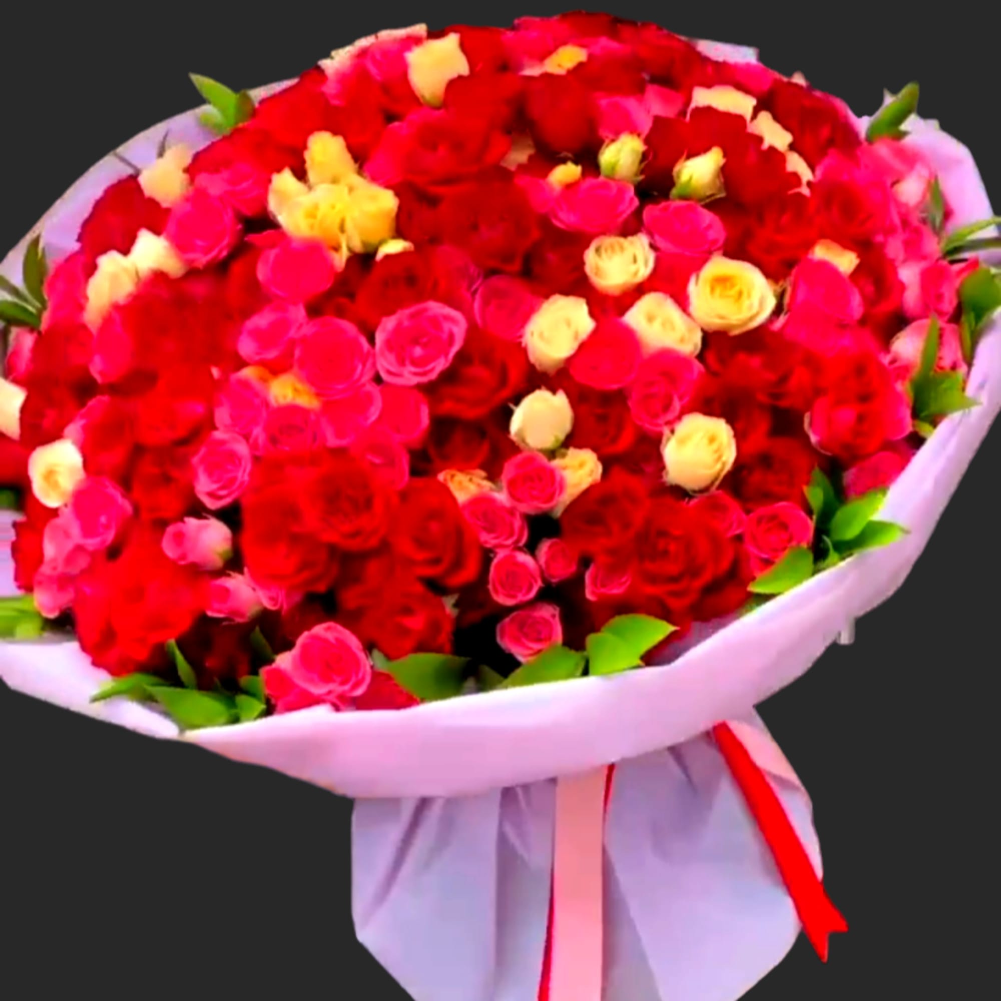 Large bouquet of red, pink, and yellow roses wrapped in white paper