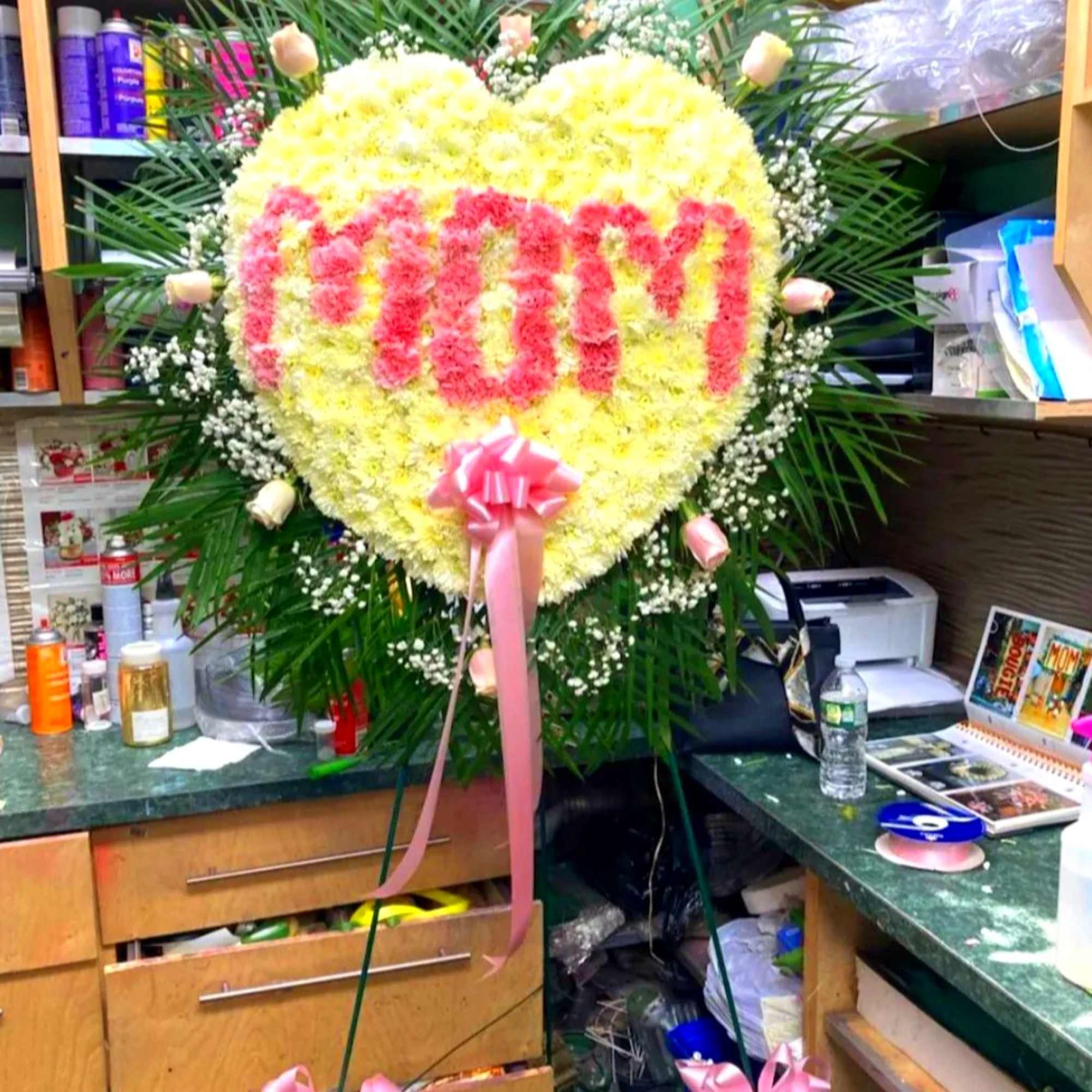 Heart-shaped floral stand with pink lettering and a pink ribbon bow