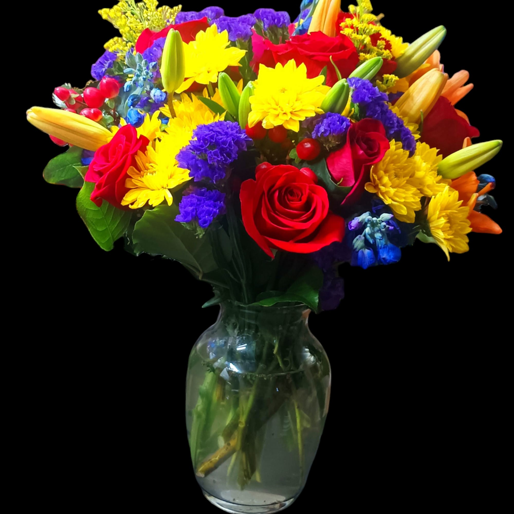 Mixed bouquet of red roses, yellow daisies, and lilies in a glass vase