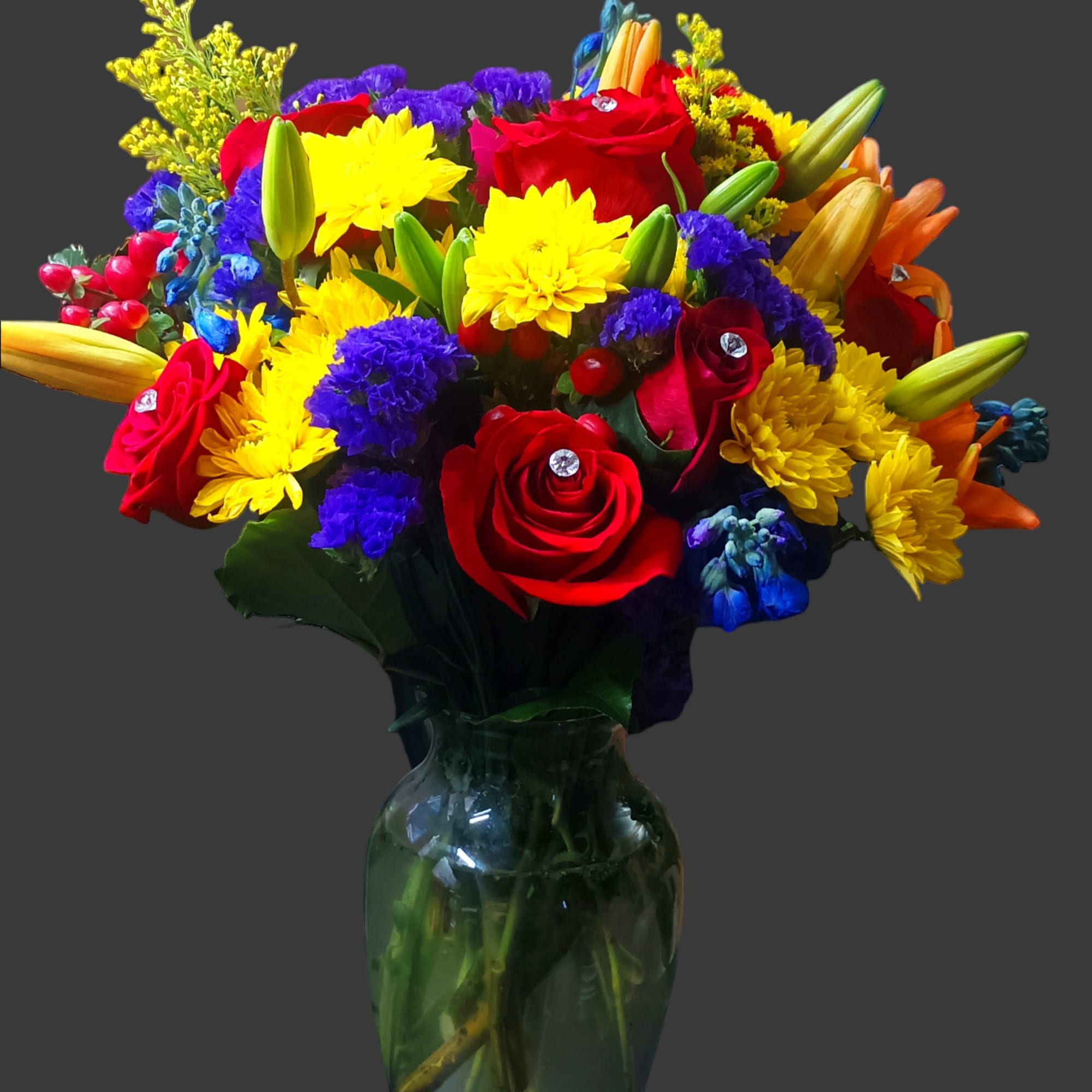 Colorful mixed bouquet of roses, lilies, and daisies in a glass vase